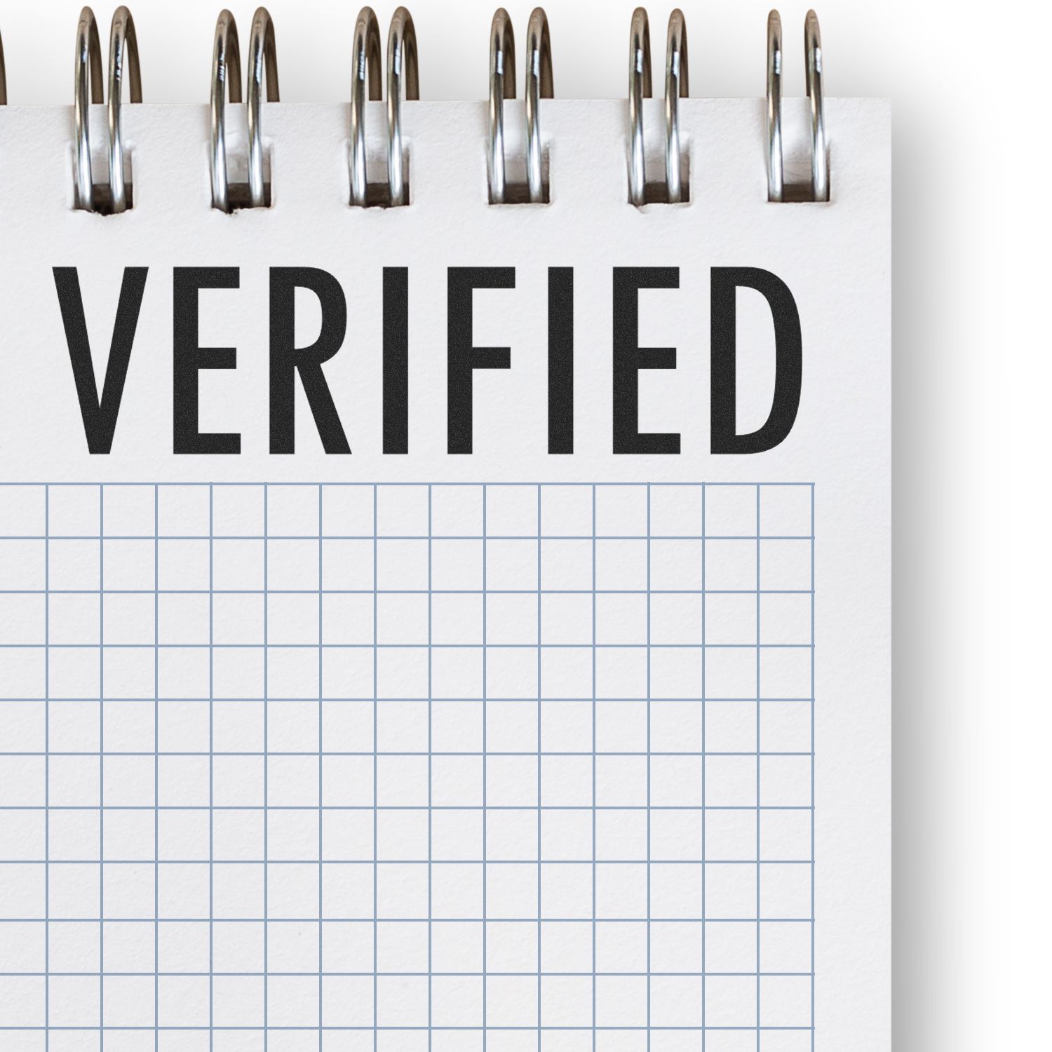 Slim Pre-Inked Verified Stamp marking a grid notebook page with the word VERIFIED in bold black letters at the top.