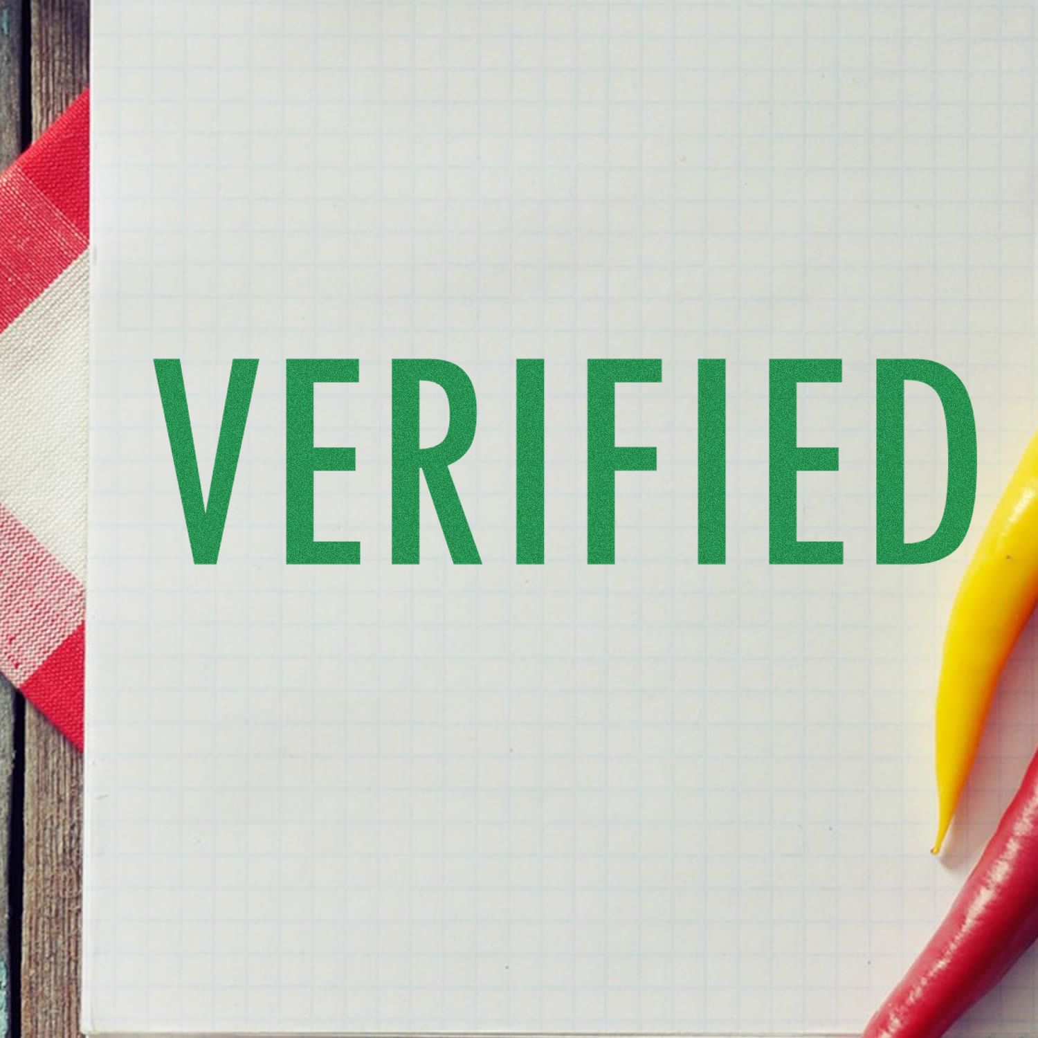 Large Self Inking Verified Stamp marking 'VERIFIED' in green on a white grid paper, with a red and white cloth and peppers in the background.