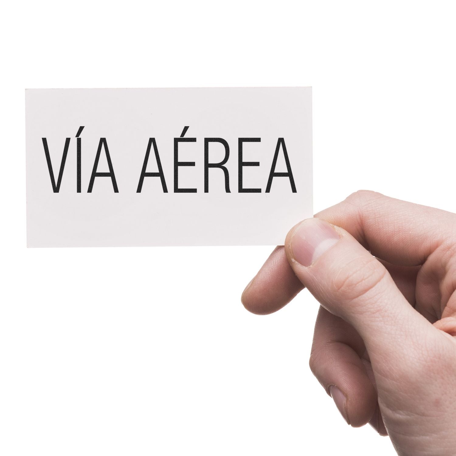 Hand holding a white card with VÍA AÉREA stamped in black, showcasing the Via Aerea Rubber Stamp in use.