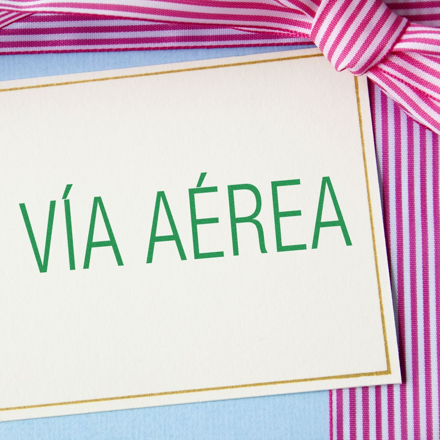 Via Aerea rubber stamp on a white card with a pink and white striped ribbon in the background.