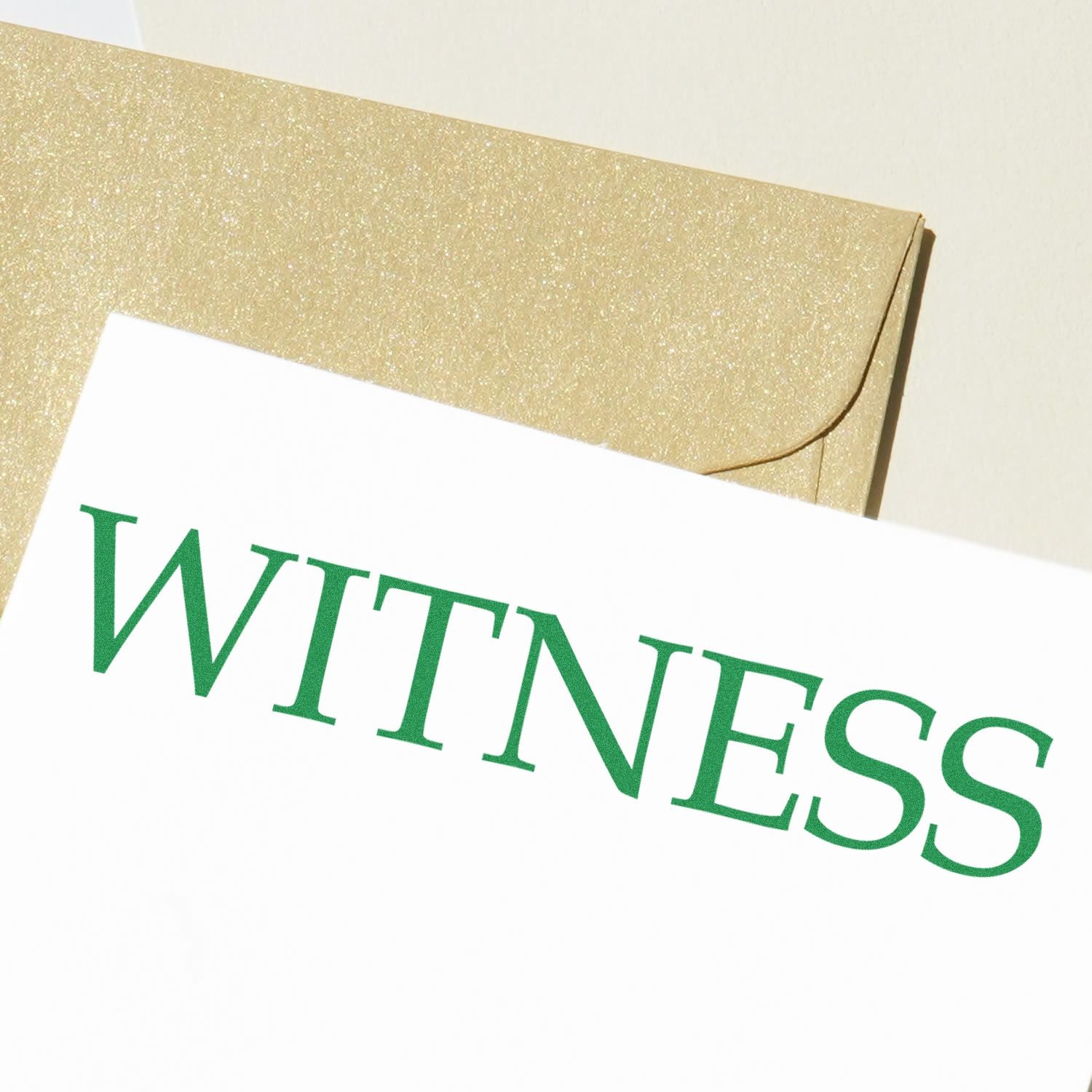 Large Witness Rubber Stamp imprint in green ink on white paper, with a golden envelope in the background.