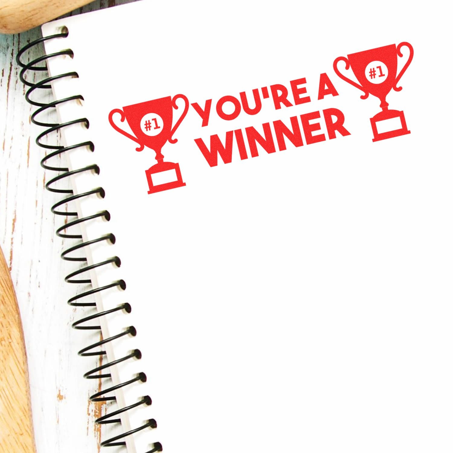 Spiral notebook with a red You're a Winner stamp featuring two trophy icons, created using the Slim Pre-Inked You're a Winner Stamp.