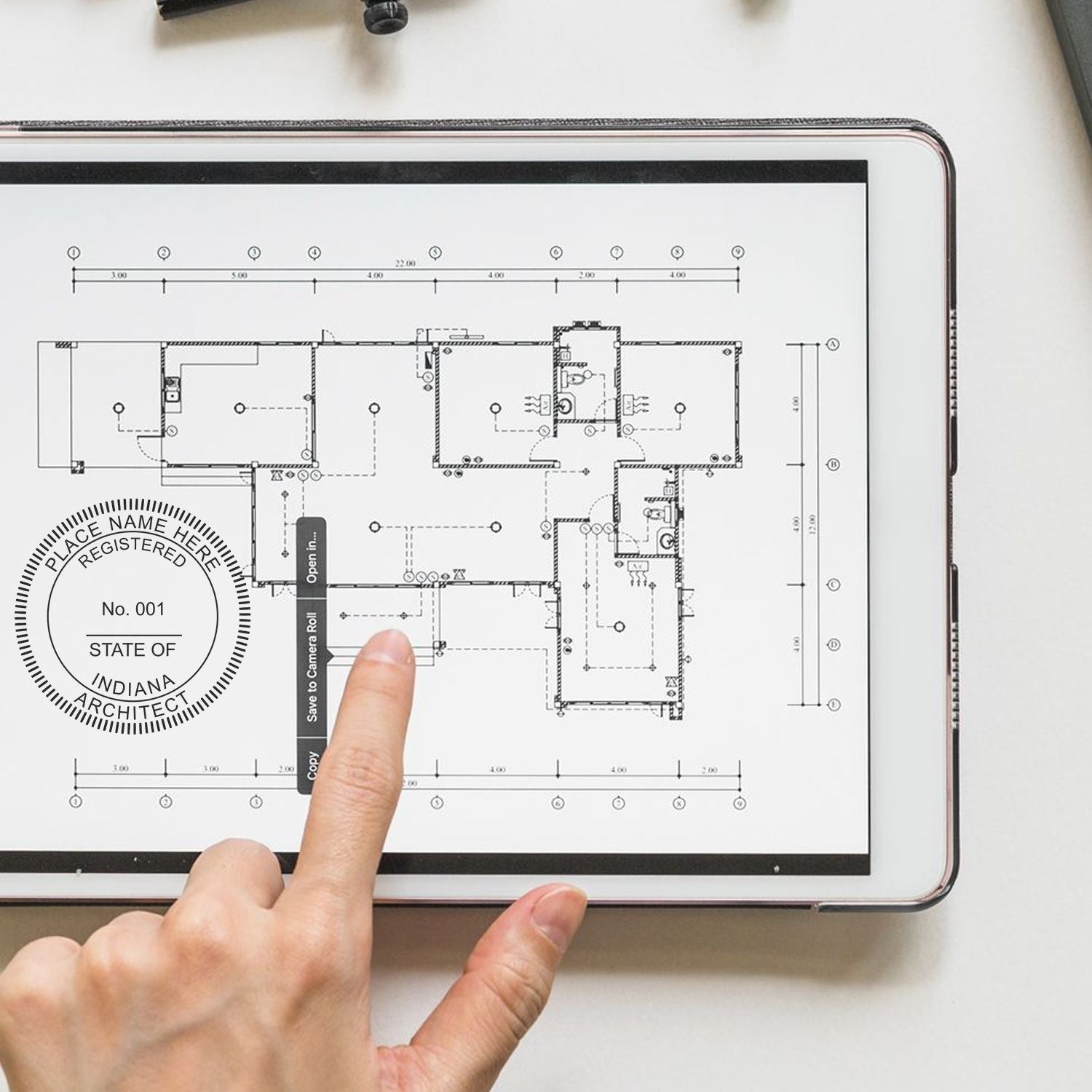 Person using Premium MaxLight Pre-Inked Indiana Architectural Stamp on a tablet displaying architectural plans.