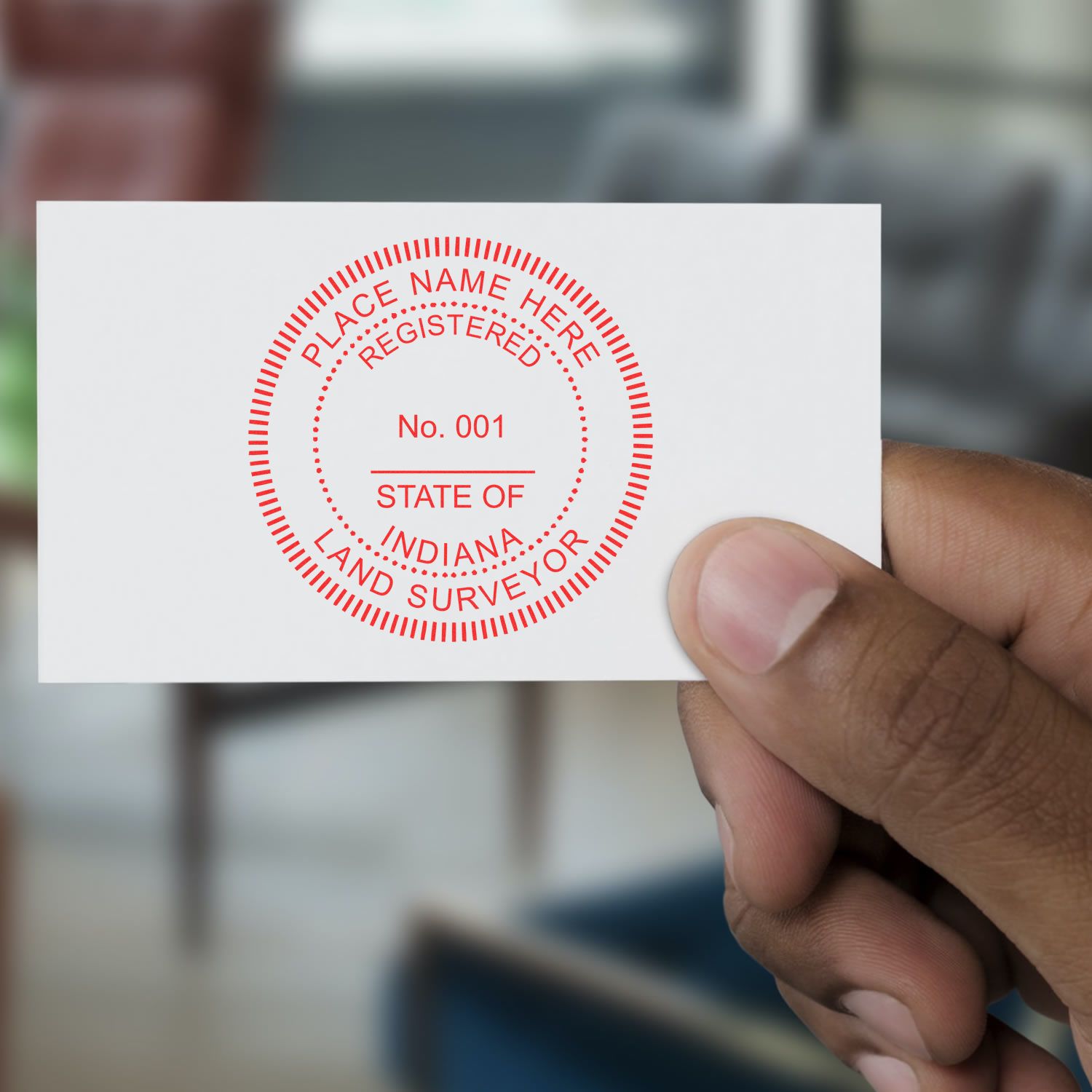 A hand holding a business card with the Indiana Land Surveyor Seal Stamp, IN PLS Stamp, displaying STATE OF INDIANA LAND SURVEYOR.