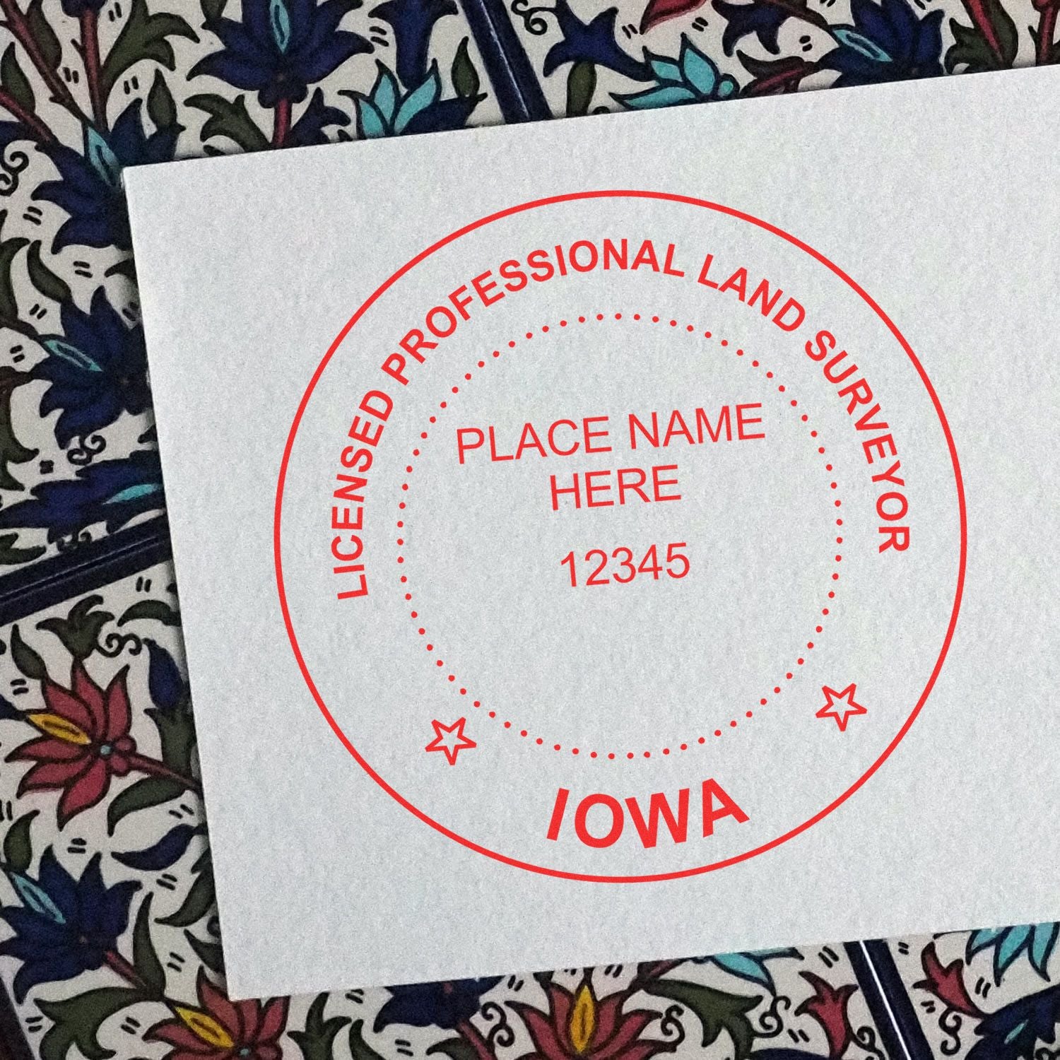 Self Inking Iowa Land Surveyor Stamp imprint on white paper with a decorative background, showing red circular text and space for customization.