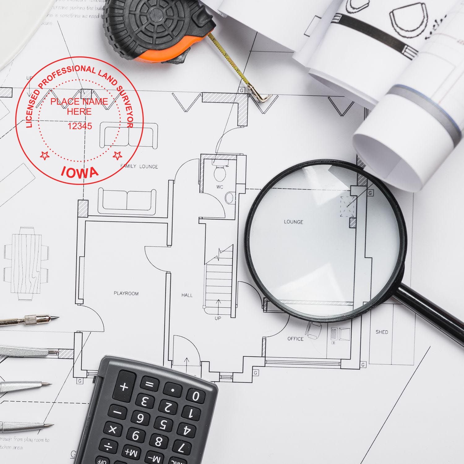 Self Inking Iowa Land Surveyor Stamp on architectural plans with a magnifying glass, calculator, and measuring tape.