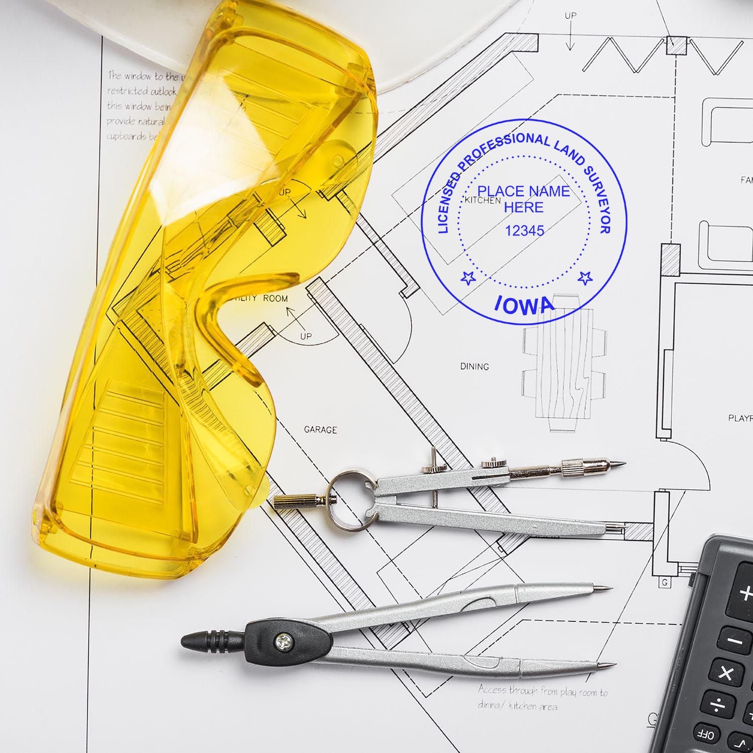 Yellow safety glasses, compass, and Self Inking Iowa Land Surveyor Stamp on architectural plans.