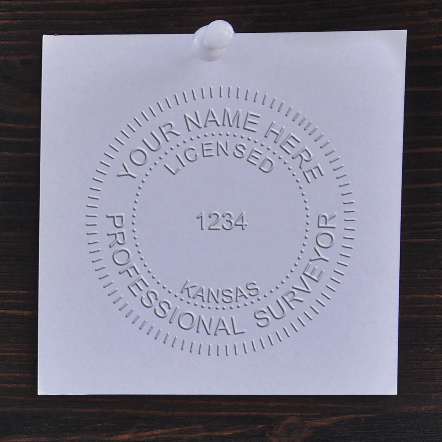 Another Example of a stamped impression of the Heavy Duty Cast Iron Kansas Land Surveyor Seal Embosser on a piece of office paper.