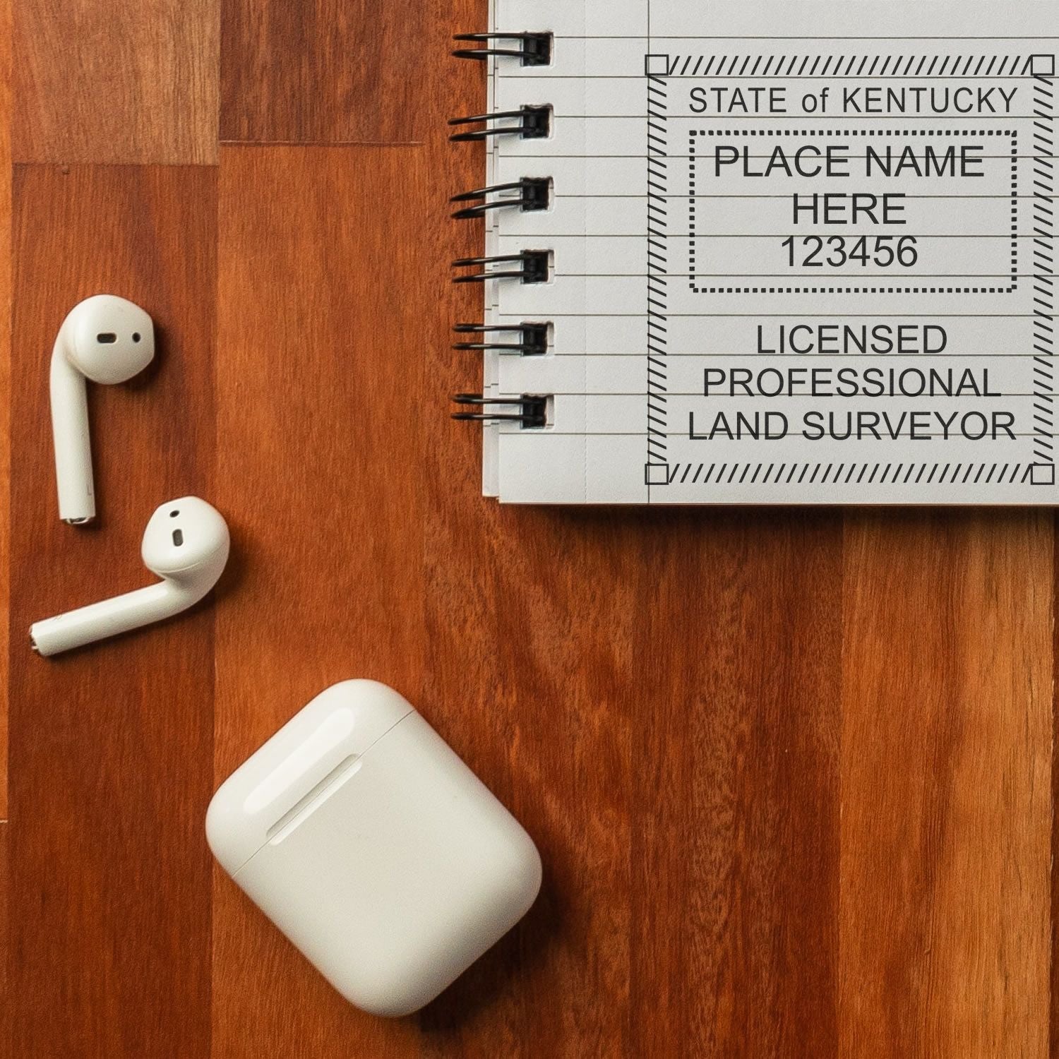 Digital Kentucky Land Surveyor Stamp, Electronic Seal for Kentucky Land Surveyor on a notepad, with earbuds and a case on a wooden surface.