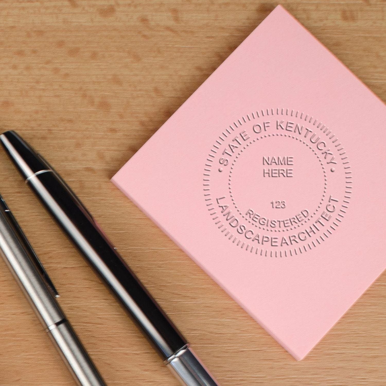 An in use photo of the Gift Kentucky Landscape Architect Seal showing a sample imprint on a cardstock