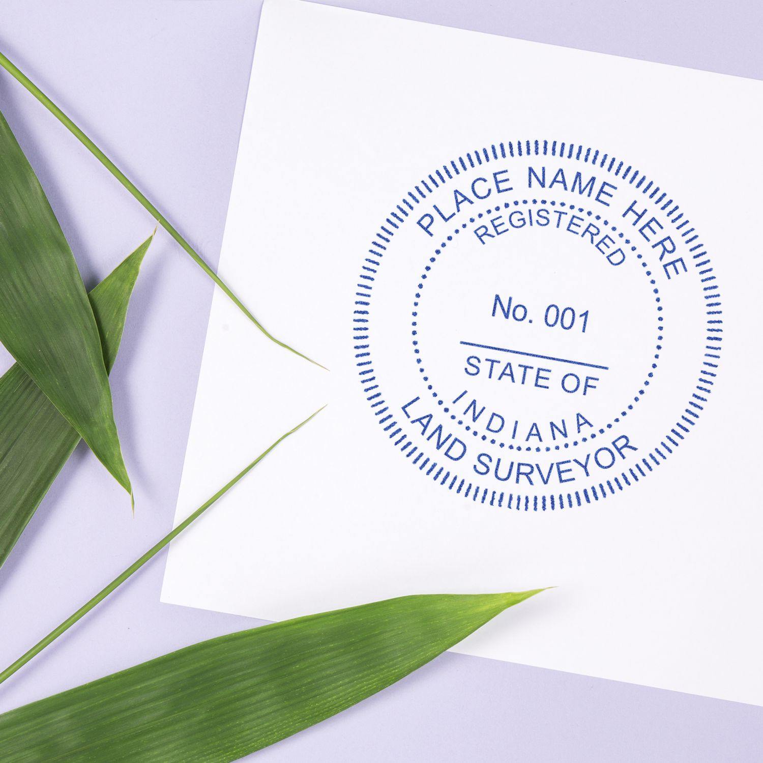 Land Surveyor Self Inking Rubber Stamp of Seal in blue ink on white paper, with green leaves on a light purple background.