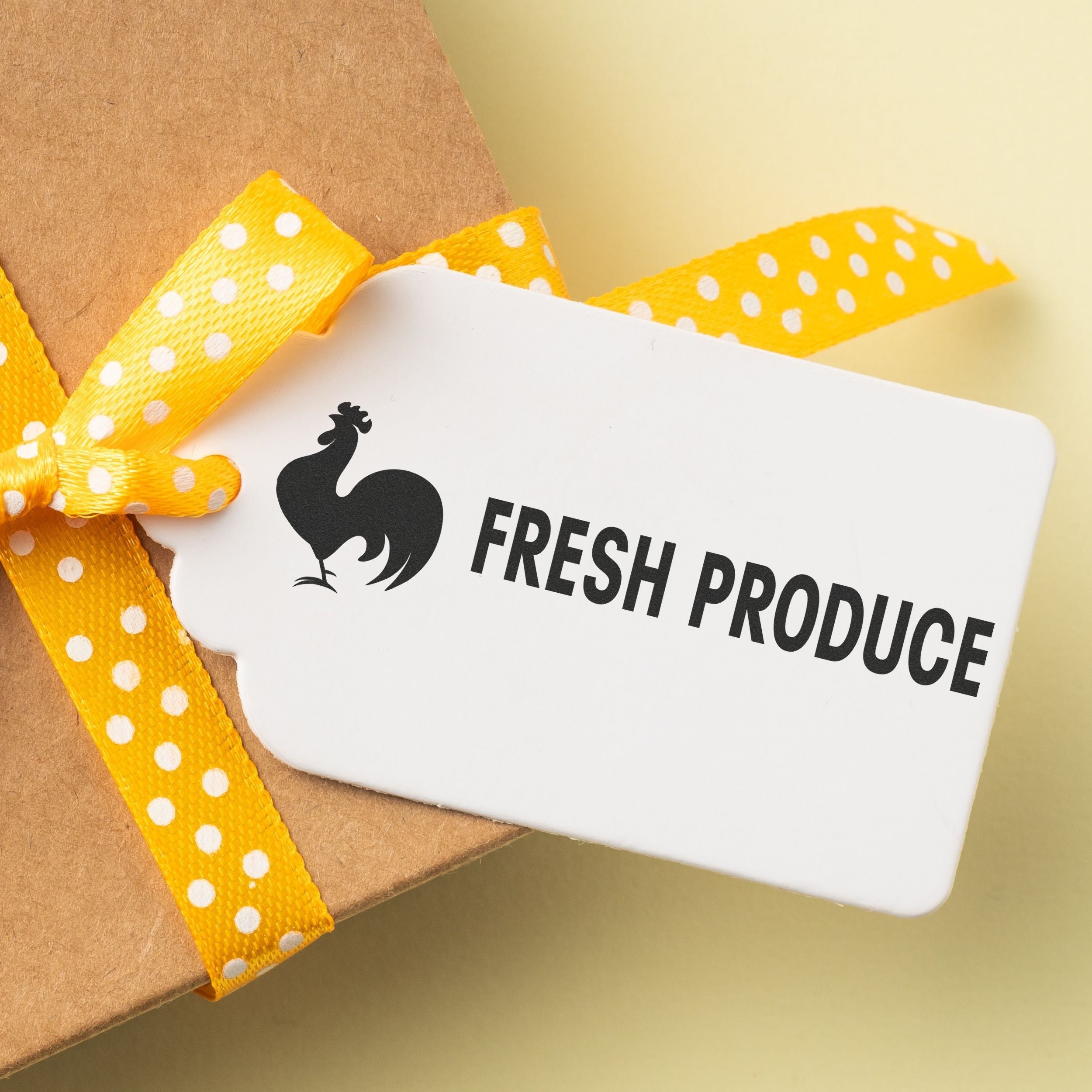 A gift tag stamped with FRESH PRODUCE using the Custom Self Inking Stamp Trodat 5205 Size 1 x 2-3/4, attached to a box with a yellow ribbon.