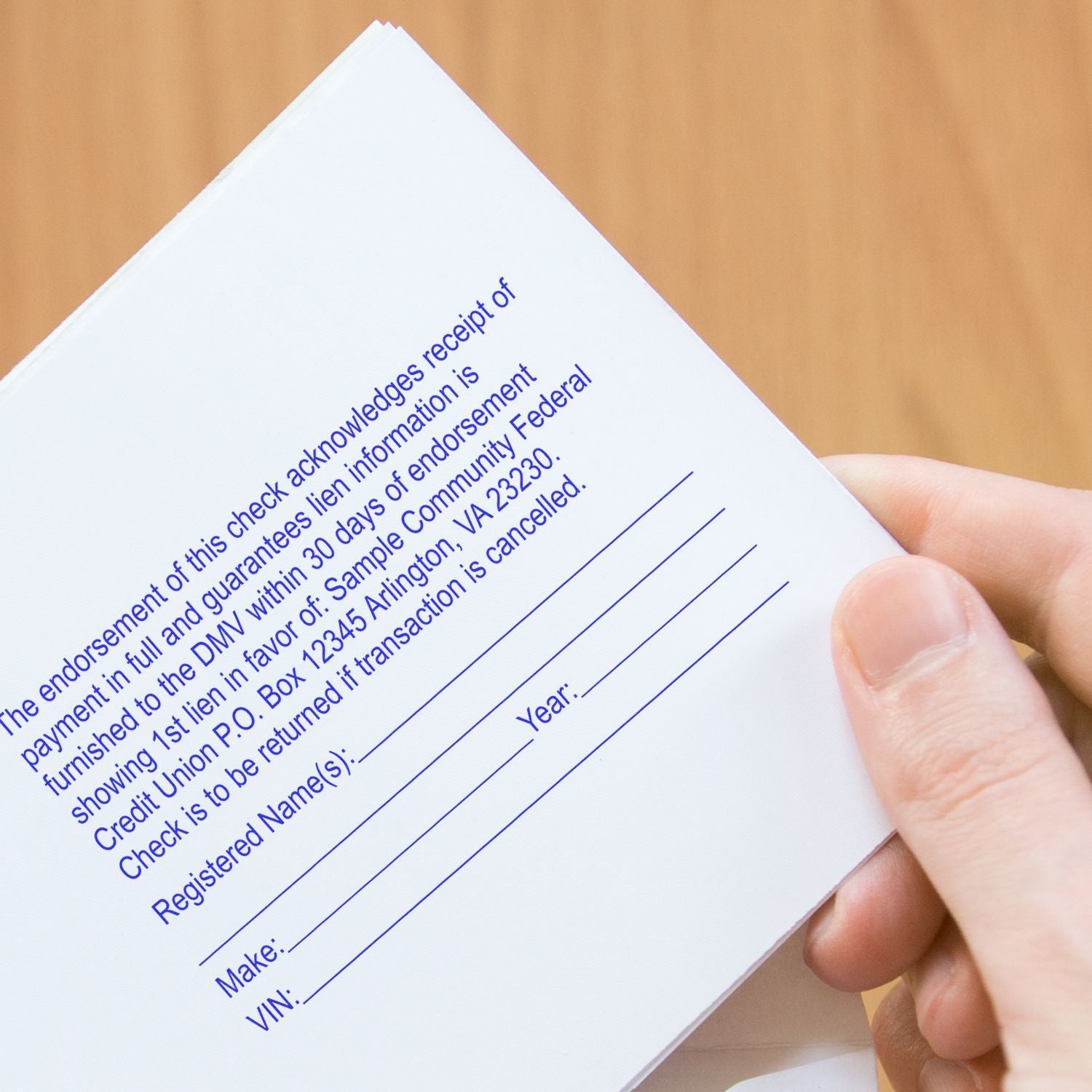 A hand holding a document stamped with a 15-Line Custom Rubber Stamp with Wood Handle, showing endorsement and registration details.