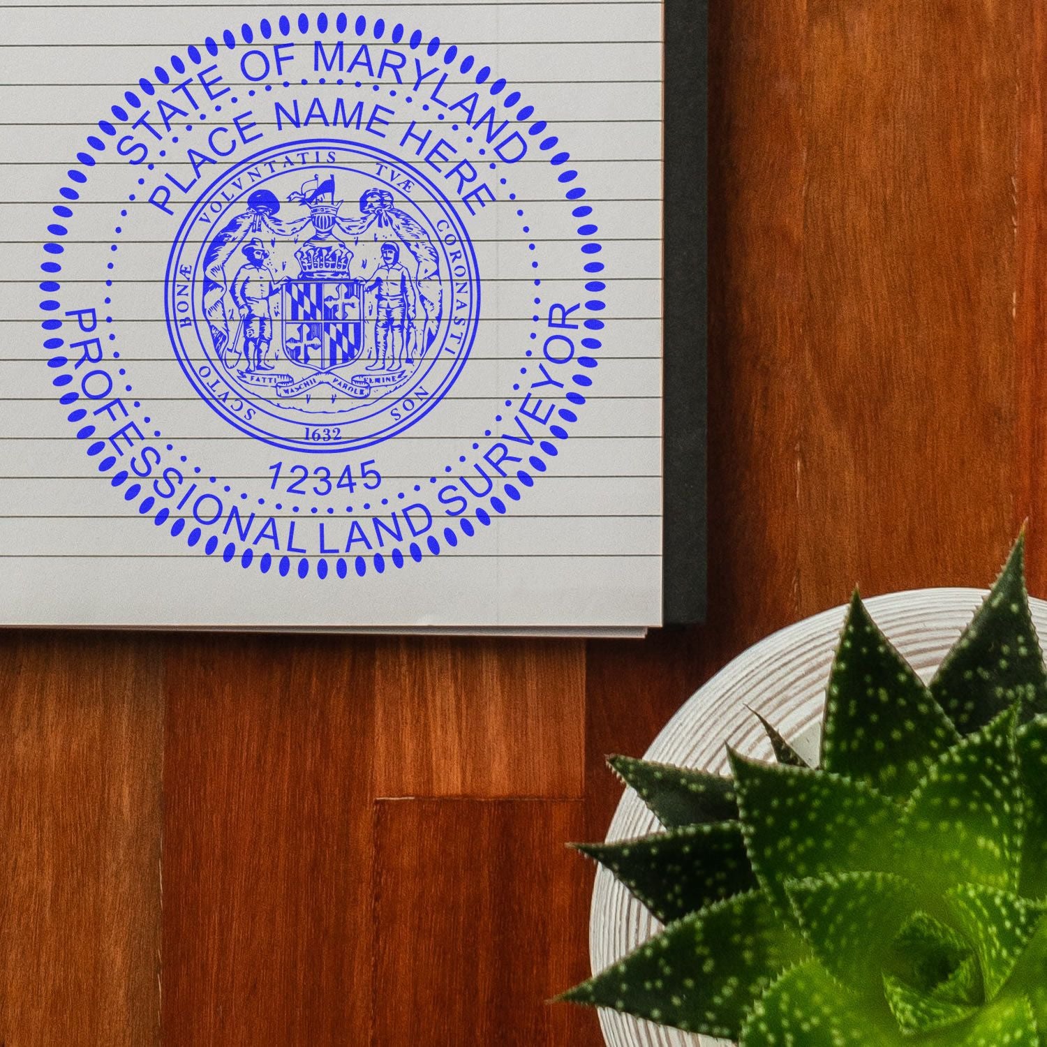 Maryland Land Surveyor Seal Stamp, MD PLS Stamp, imprinted in blue ink on a notebook page, placed on a wooden desk next to a green plant.