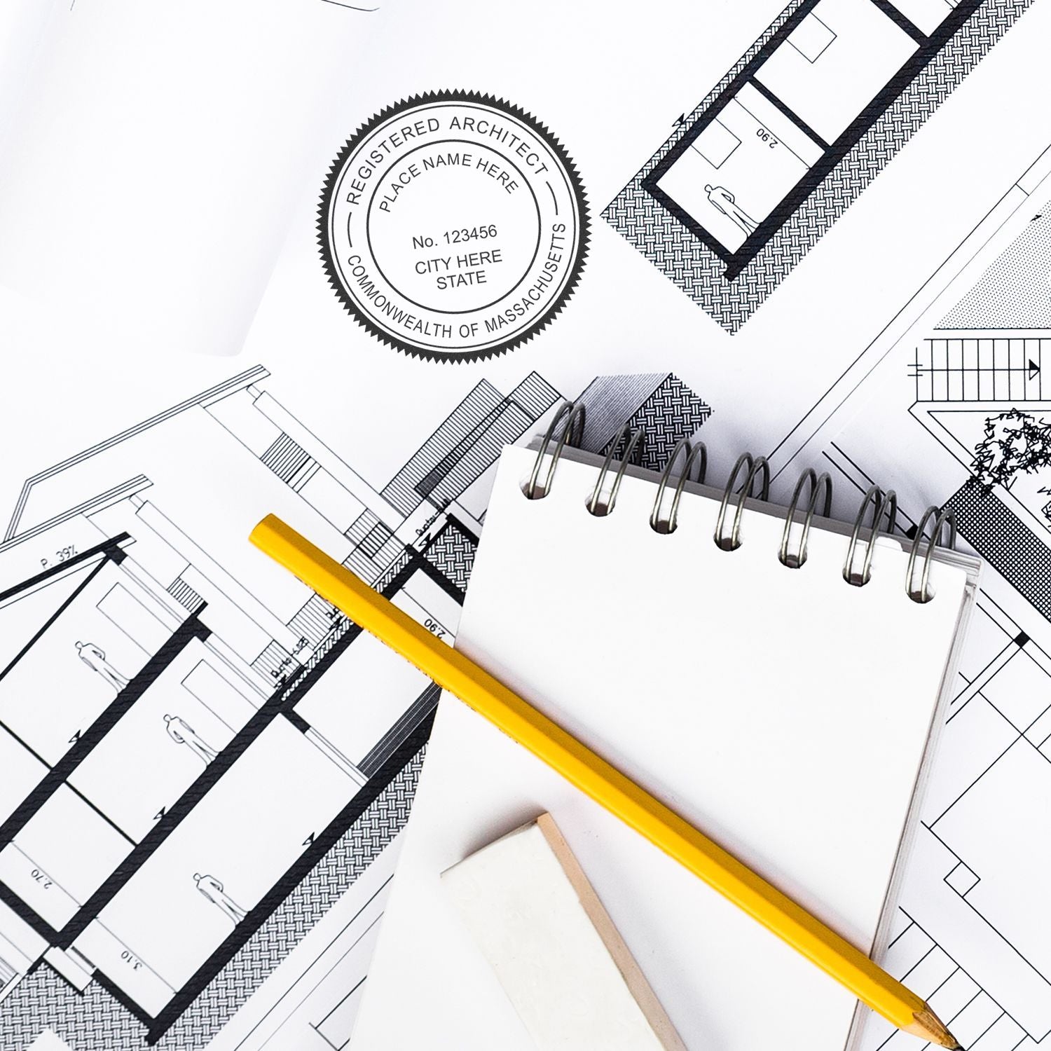 Self Inking Massachusetts Architect Stamp in use on architectural blueprints with a pencil, notepad, and eraser nearby.