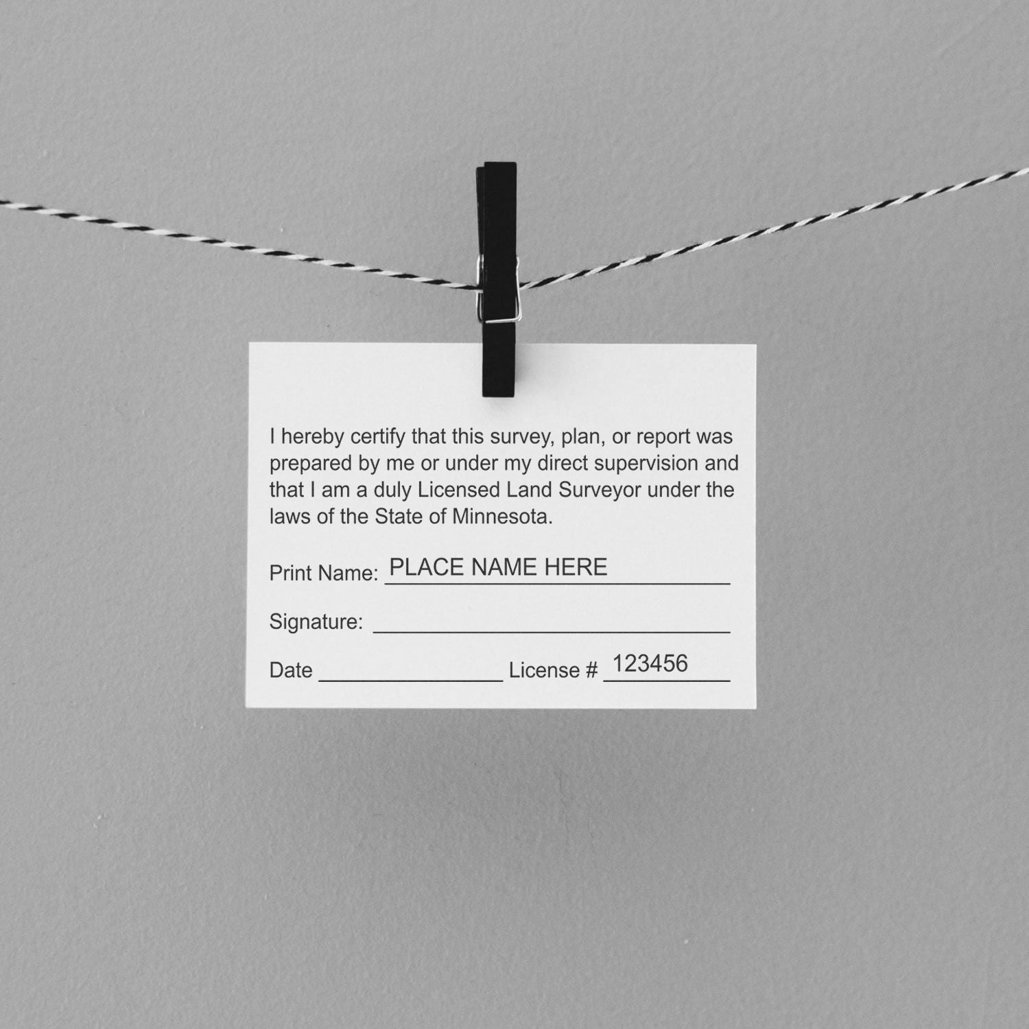 A card with text certifying a land survey, clipped to a string, featuring the Digital Minnesota Land Surveyor Stamp, Electronic Seal for Minnesota Land Surveyor.