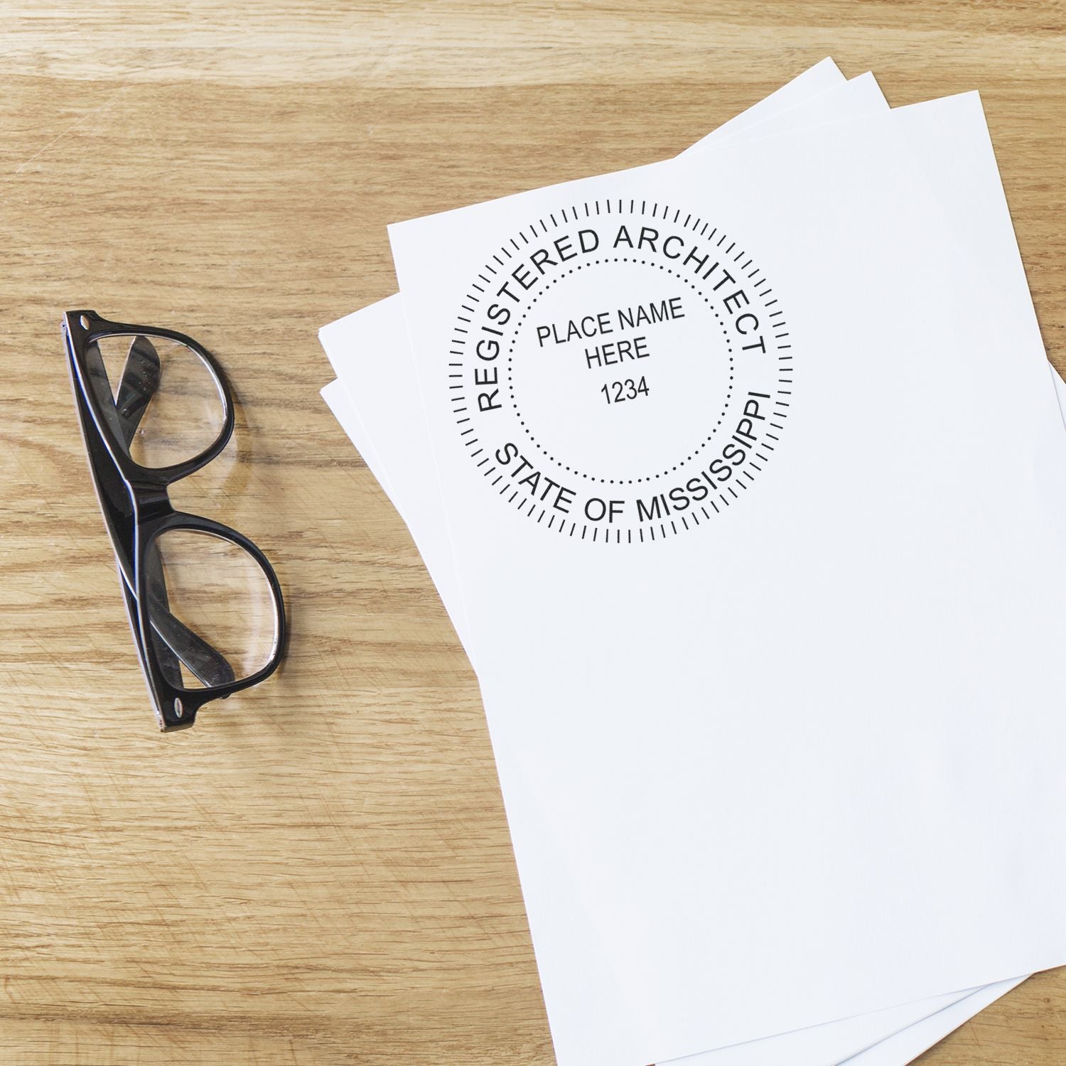 Mississippi Architect Seal Stamp on white paper beside black eyeglasses on a wooden table.