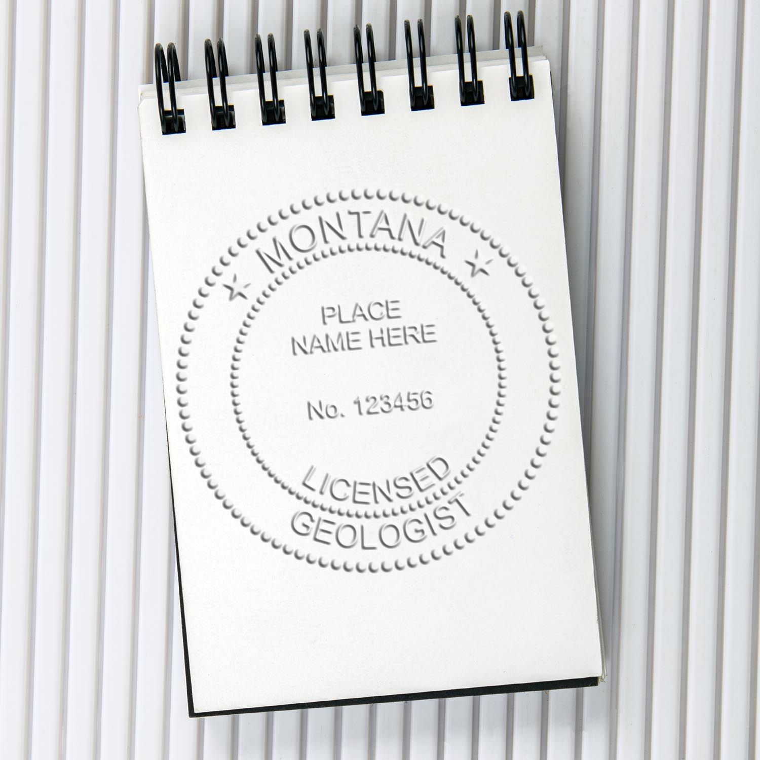 An in use photo of the Hybrid Montana Geologist Seal showing a sample imprint on a cardstock