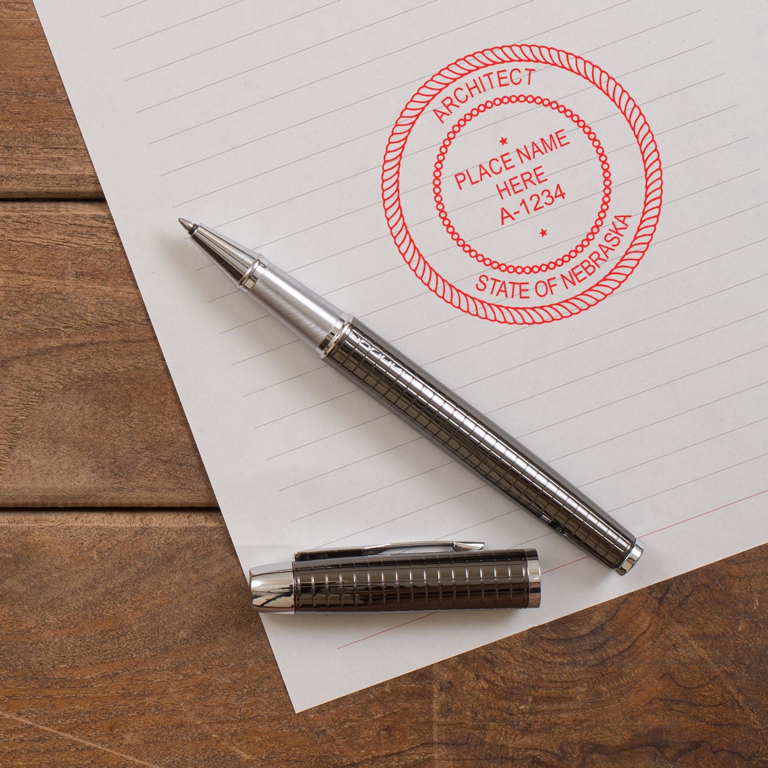 Premium MaxLight Pre-Inked Nebraska Architectural Stamp in red ink on paper, next to a silver pen and pen cap on a wooden surface.