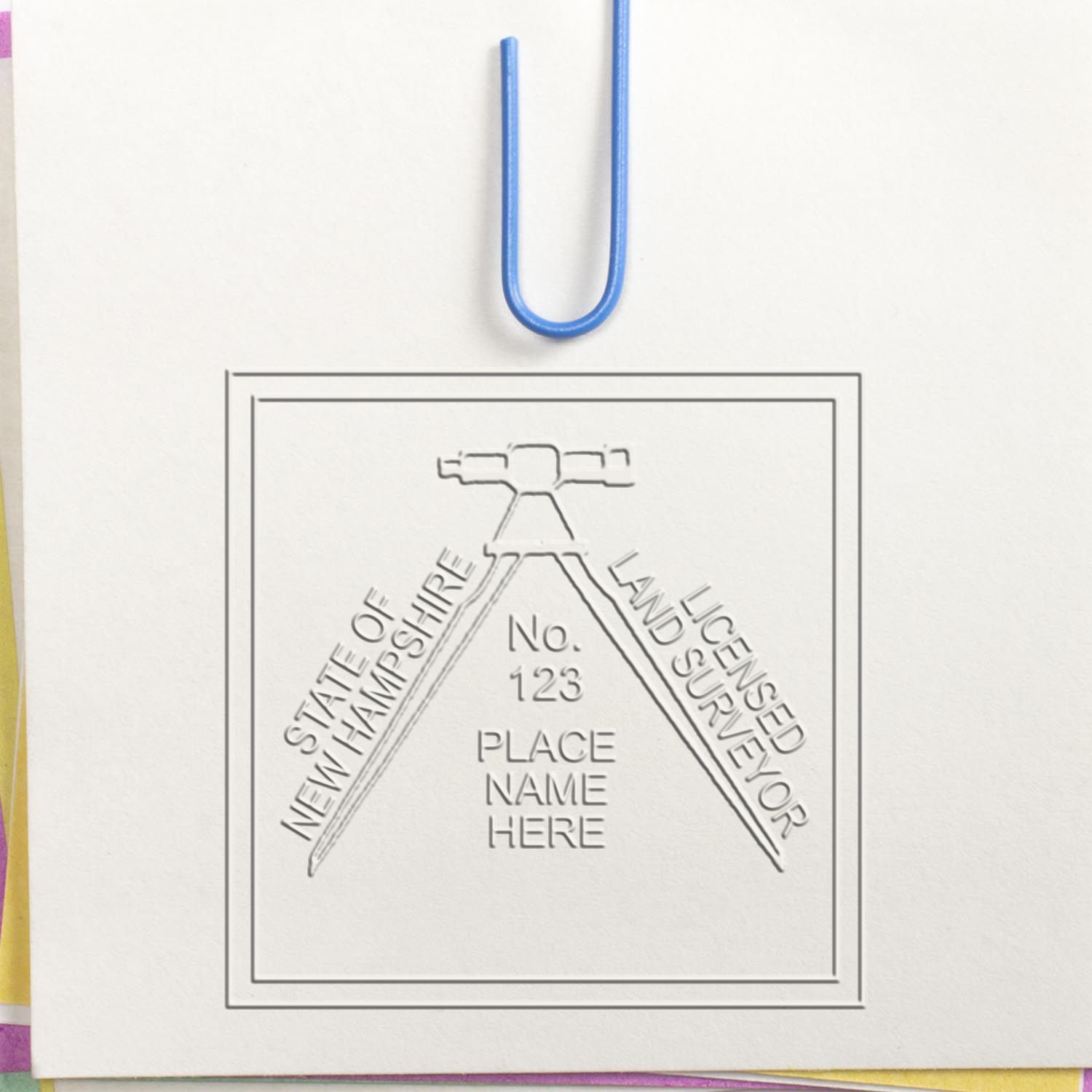 A lifestyle photo showing a stamped image of the Handheld New Hampshire Land Surveyor Seal on a piece of paper