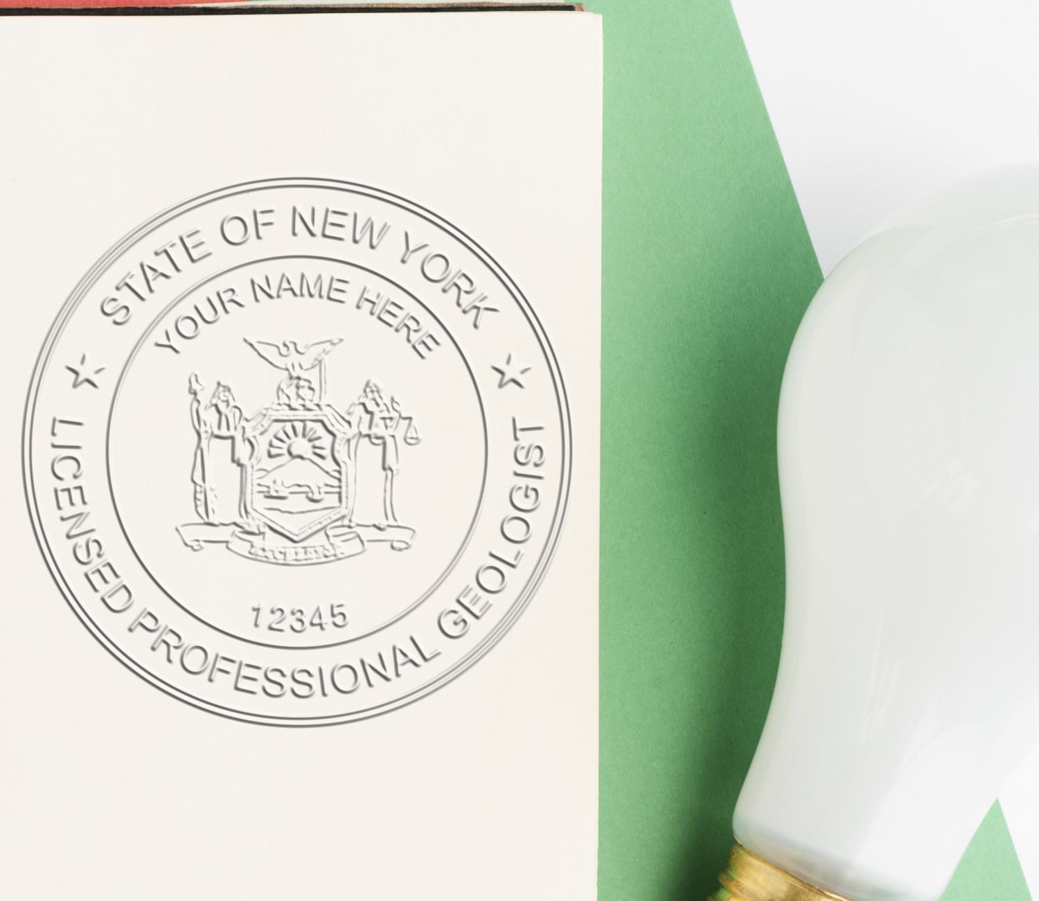 A lifestyle photo showing a stamped image of the Heavy Duty Cast Iron New York Geologist Seal Embosser on a piece of paper