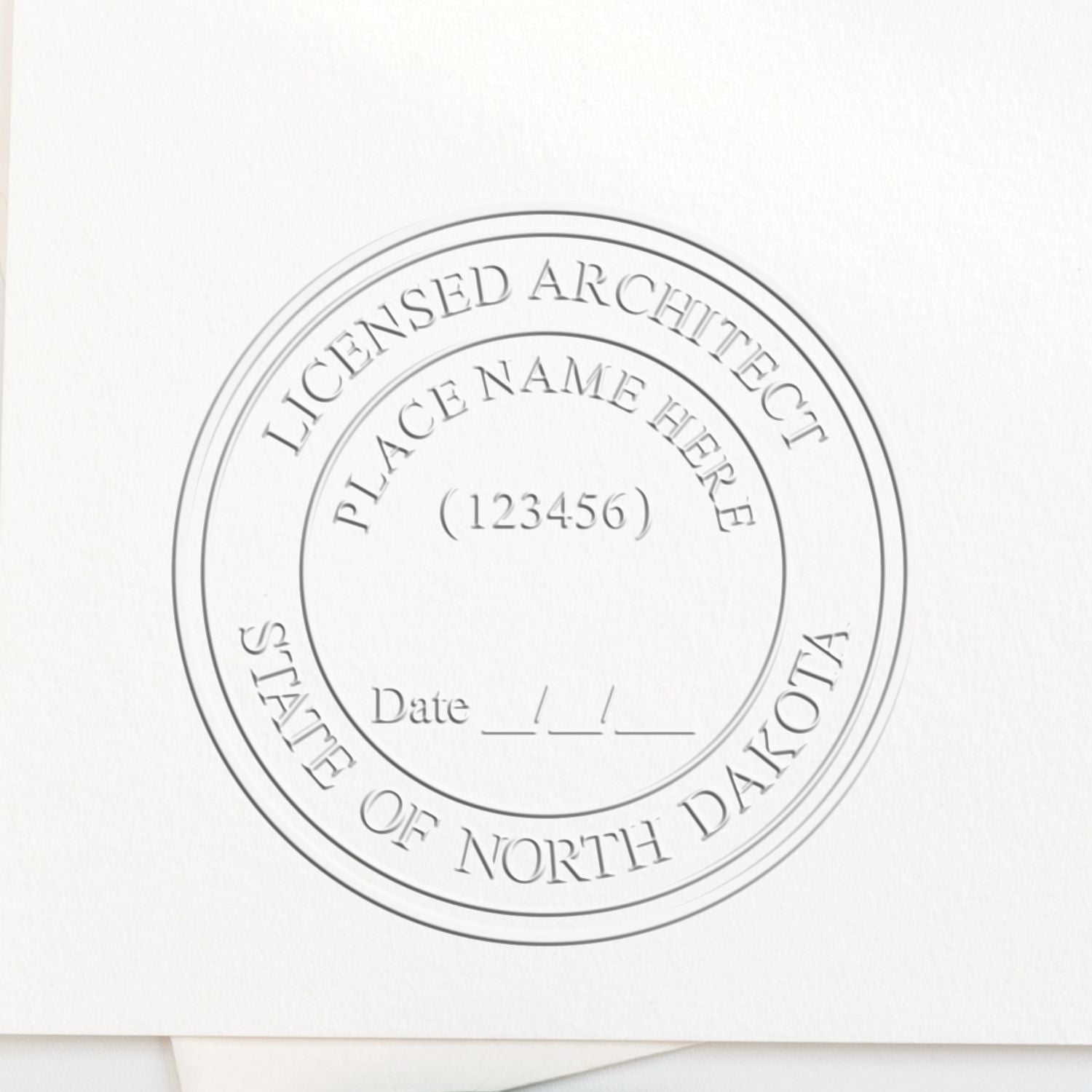 A lifestyle photo showing a stamped image of the Handheld North Dakota Architect Seal Embosser on a piece of paper