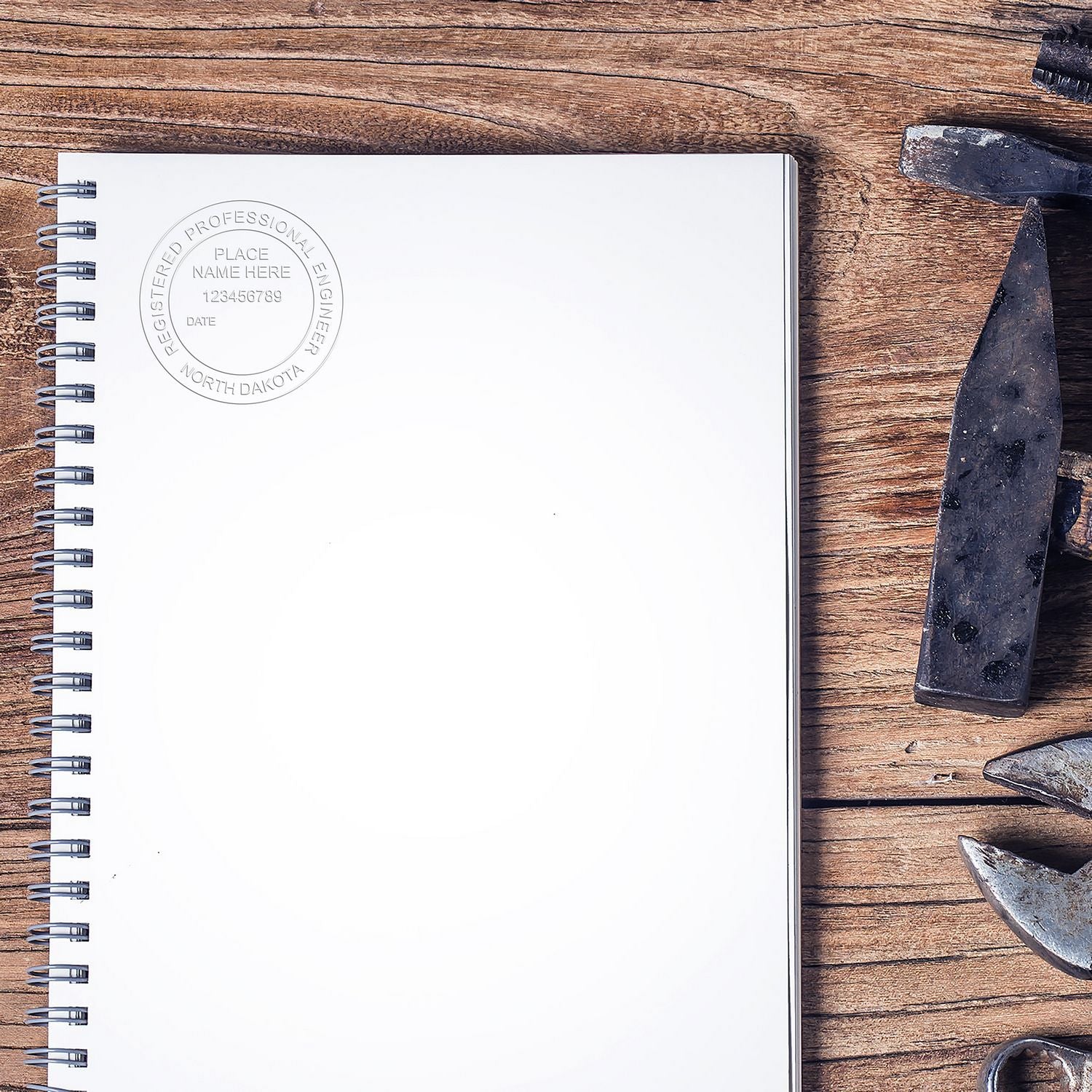 A Professional Engineer Soft Seal Embosser imprint on a white spiral notebook, placed on a wooden surface with various tools nearby.