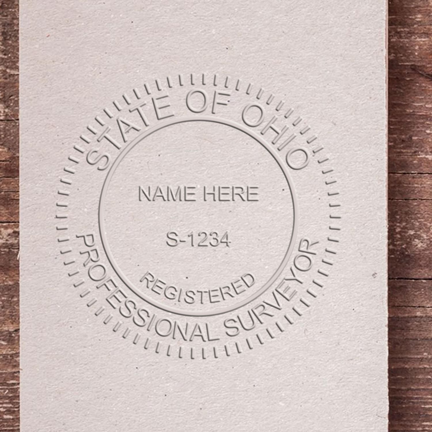 A lifestyle photo showing a stamped image of the Ohio Desk Surveyor Seal Embosser on a piece of paper