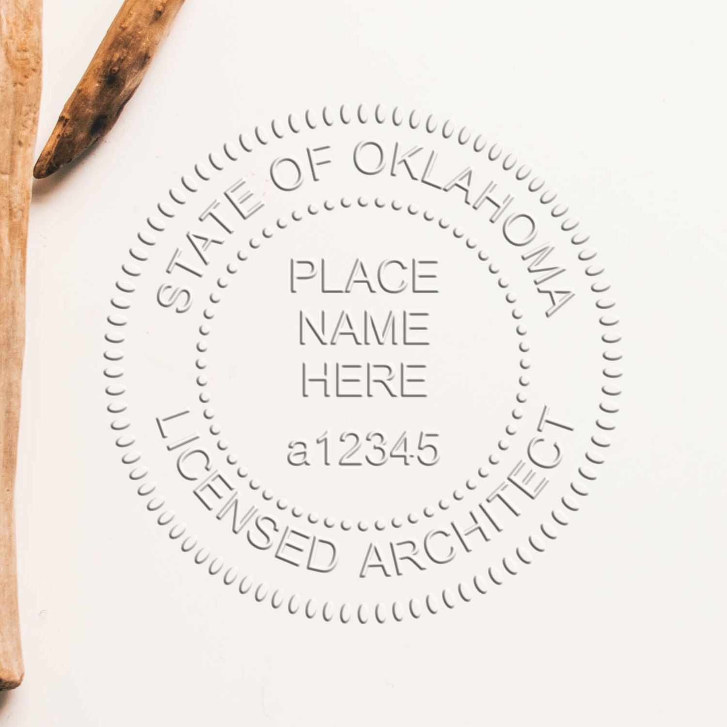 A lifestyle photo showing a stamped image of the Handheld Oklahoma Architect Seal Embosser on a piece of paper