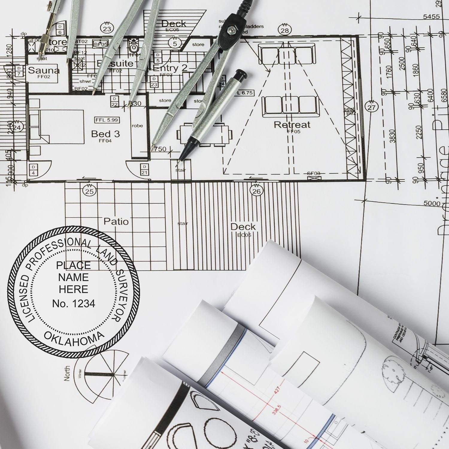 Architectural plans with a Premium MaxLight Pre-Inked Oklahoma Surveyors Stamp, compass, and rolled blueprints on a desk.