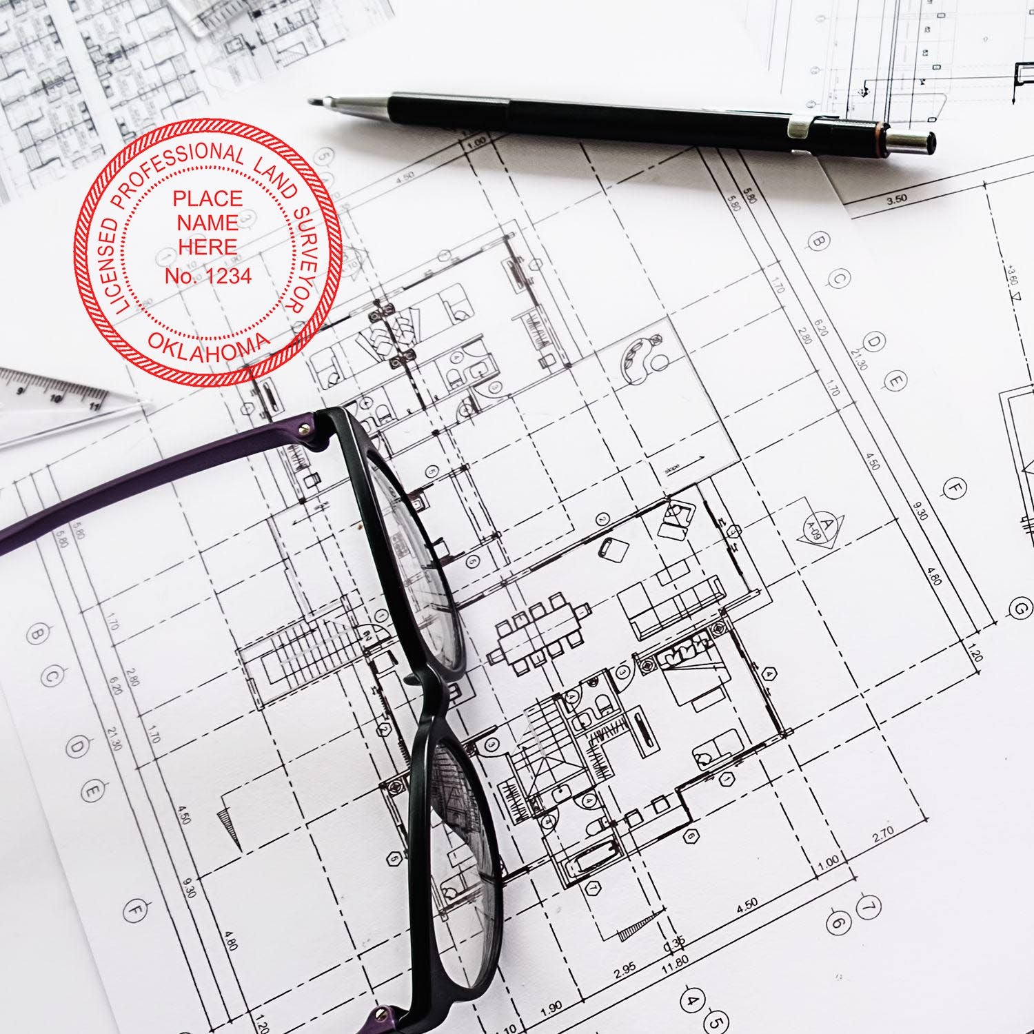 Oklahoma Land Surveyor Seal Stamp on architectural blueprints with glasses and a pen nearby.