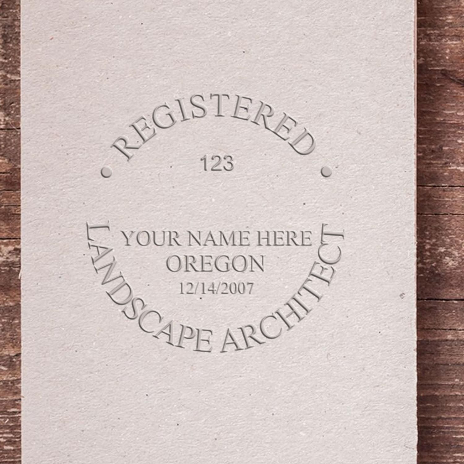 An in use photo of the Hybrid Oregon Landscape Architect Seal showing a sample imprint on a cardstock