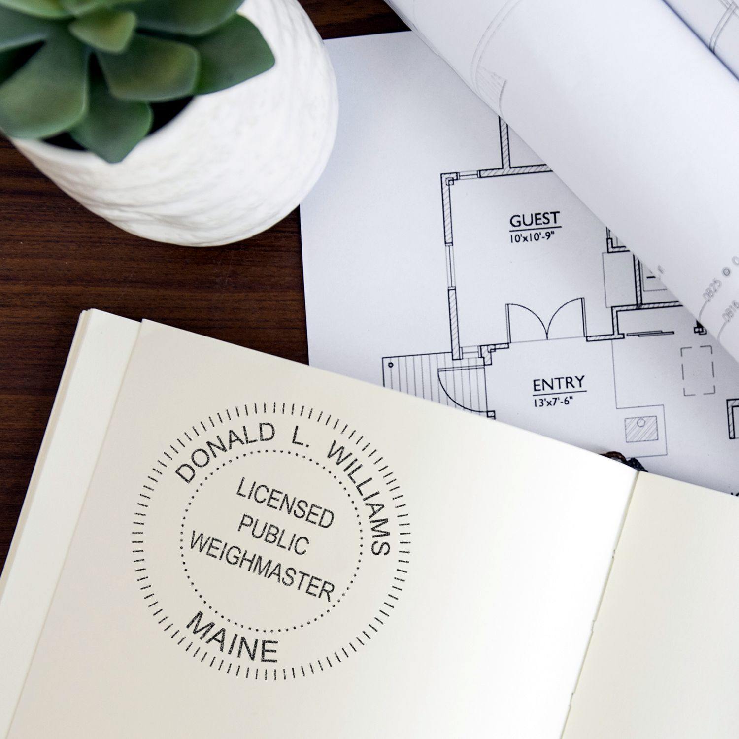 Public Weighmaster eSeal Electronic Image Stamp of Seal in use on a document, with architectural plans and a plant in the background.