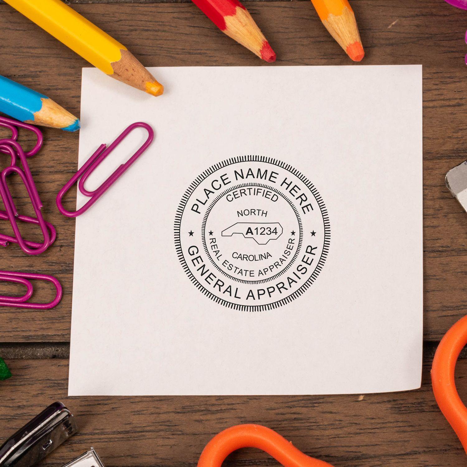 Real Estate Appraiser Slim Pre Inked Rubber Stamp of Seal on white paper, surrounded by colorful office supplies on a wooden desk.