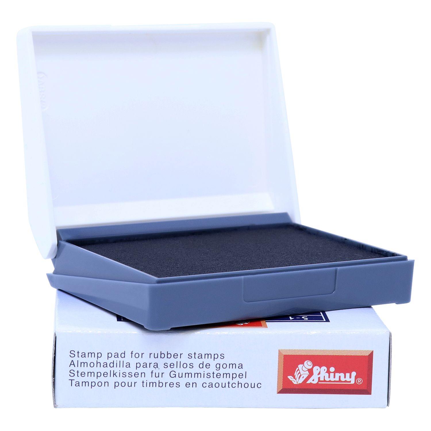 Rubber Stamp Ink Pad 00 Size 1-1/2 x 2-3/4 in black, open with a white lid, placed on a box with multilingual text and the Shiny logo.