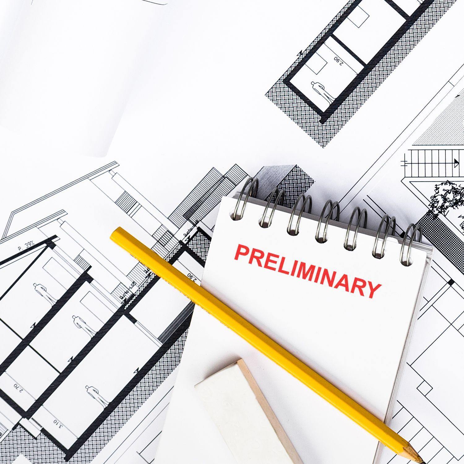 Slim Pre-Inked Preliminary Stamp used on a notepad with architectural blueprints, a yellow pencil, and an eraser in the background.