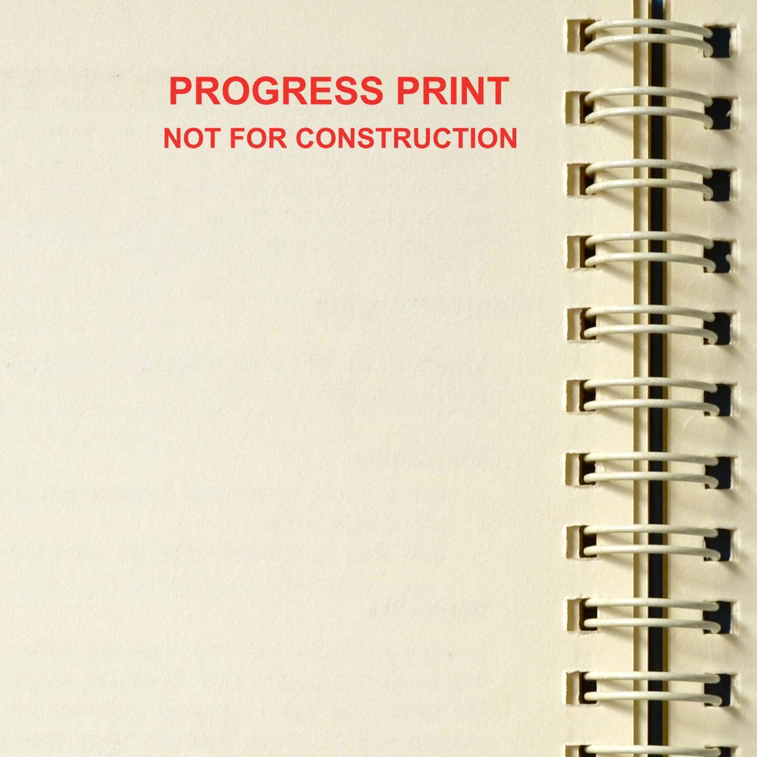 Slim Pre-Inked Progress Print Stamp marking PROGRESS PRINT NOT FOR CONSTRUCTION in red ink on a spiral-bound notebook page.