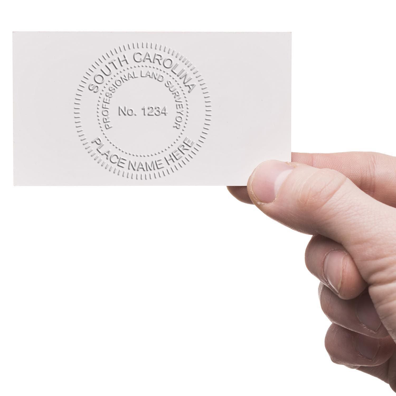 Hand holding a card embossed with South Carolina Professional Land Surveyor using the Land Surveyor Cast Iron Desk Seal Embosser.