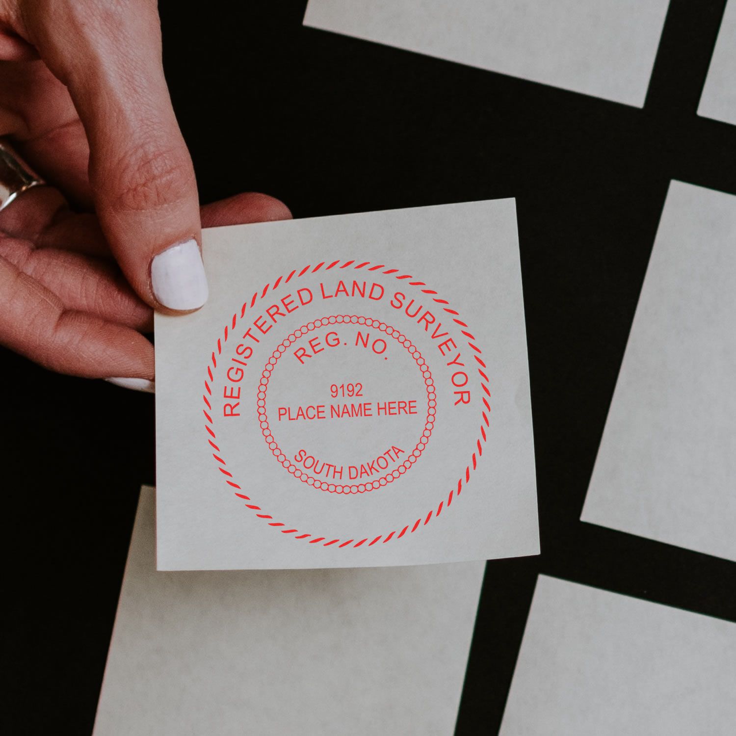 A lifestyle photo showing a stamped image of the Slim Pre-Inked South Dakota Land Surveyor Seal Stamp on a piece of paper