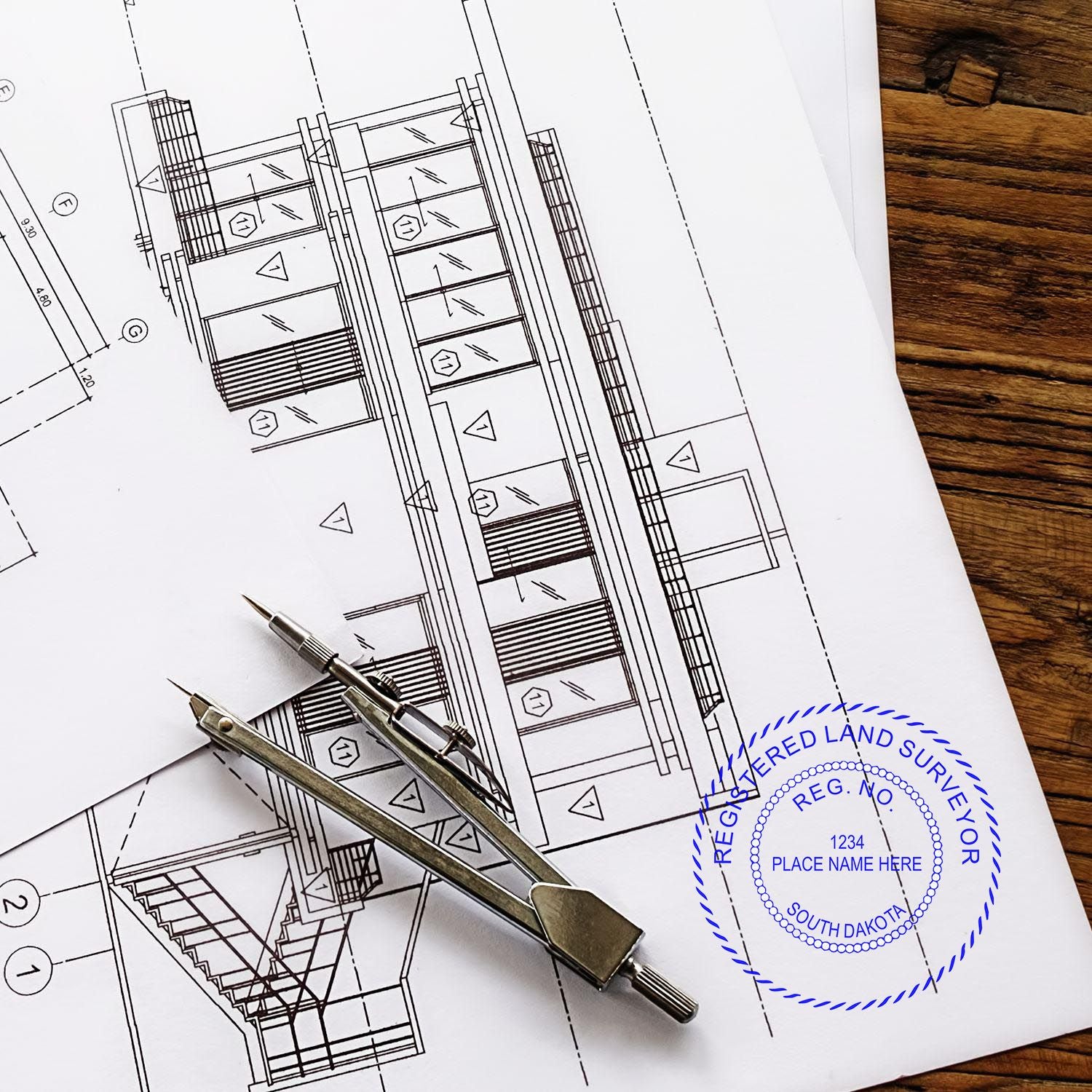 Blueprint with a compass and Digital South Dakota Land Surveyor Stamp, Electronic Seal for South Dakota Land Surveyor on a wooden table.