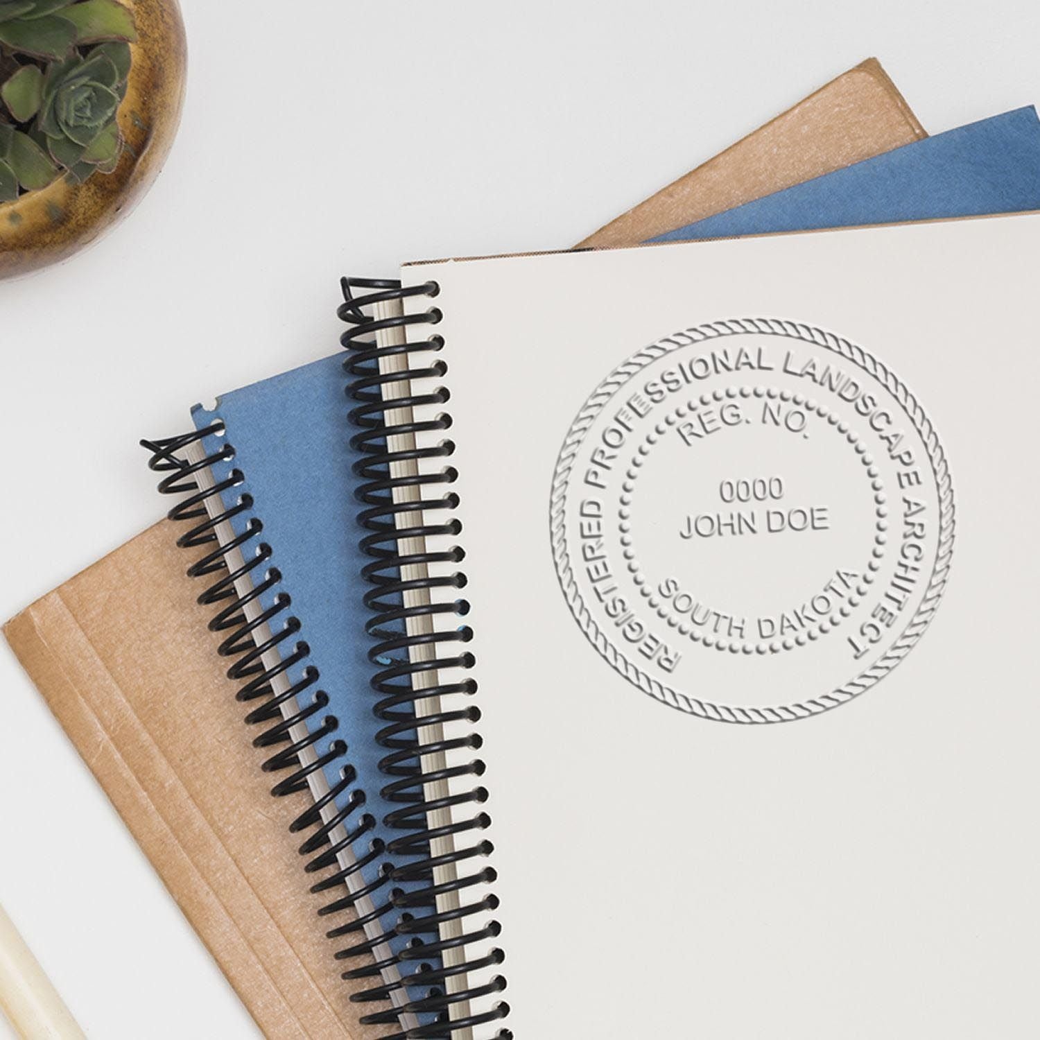 An in use photo of the Gift South Dakota Landscape Architect Seal showing a sample imprint on a cardstock