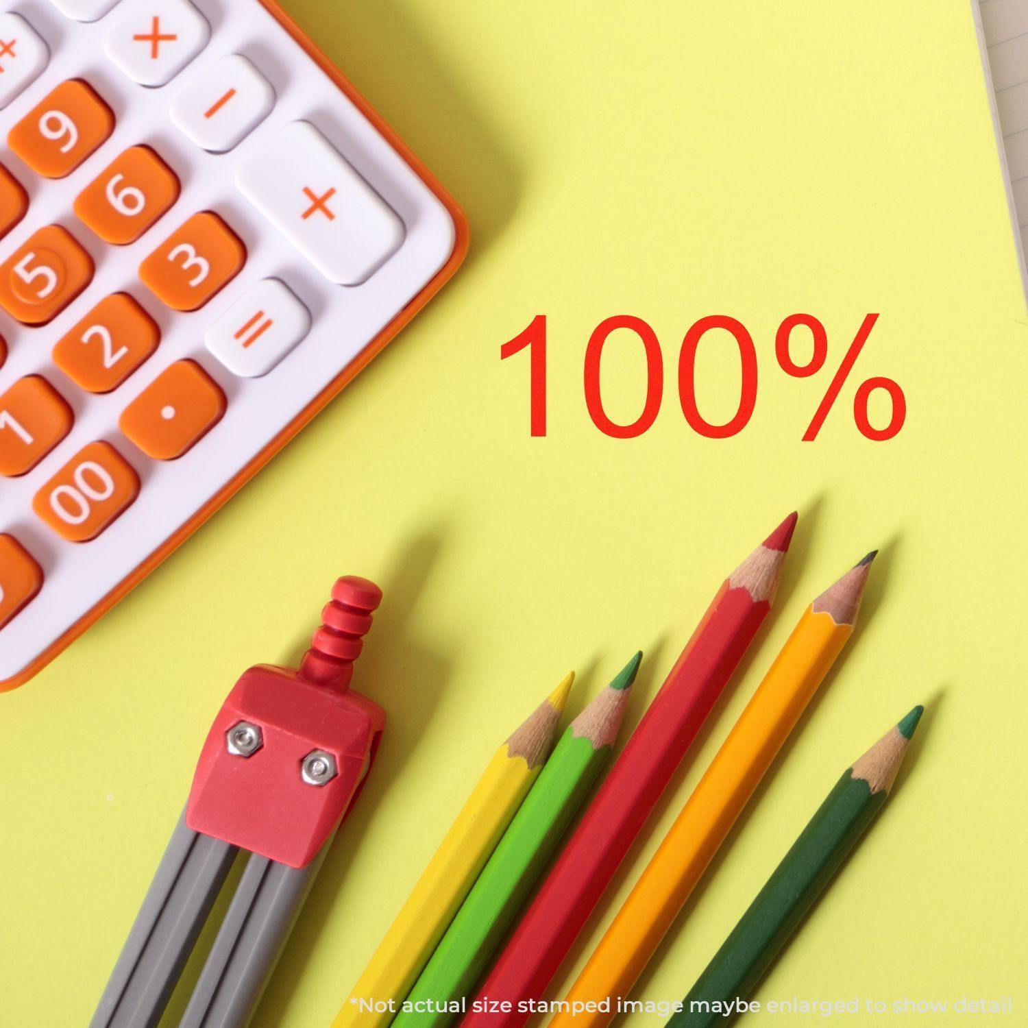 Large 100 Percent Rubber Stamp in use, showing a red 100% mark on yellow paper, next to a calculator and colored pencils.