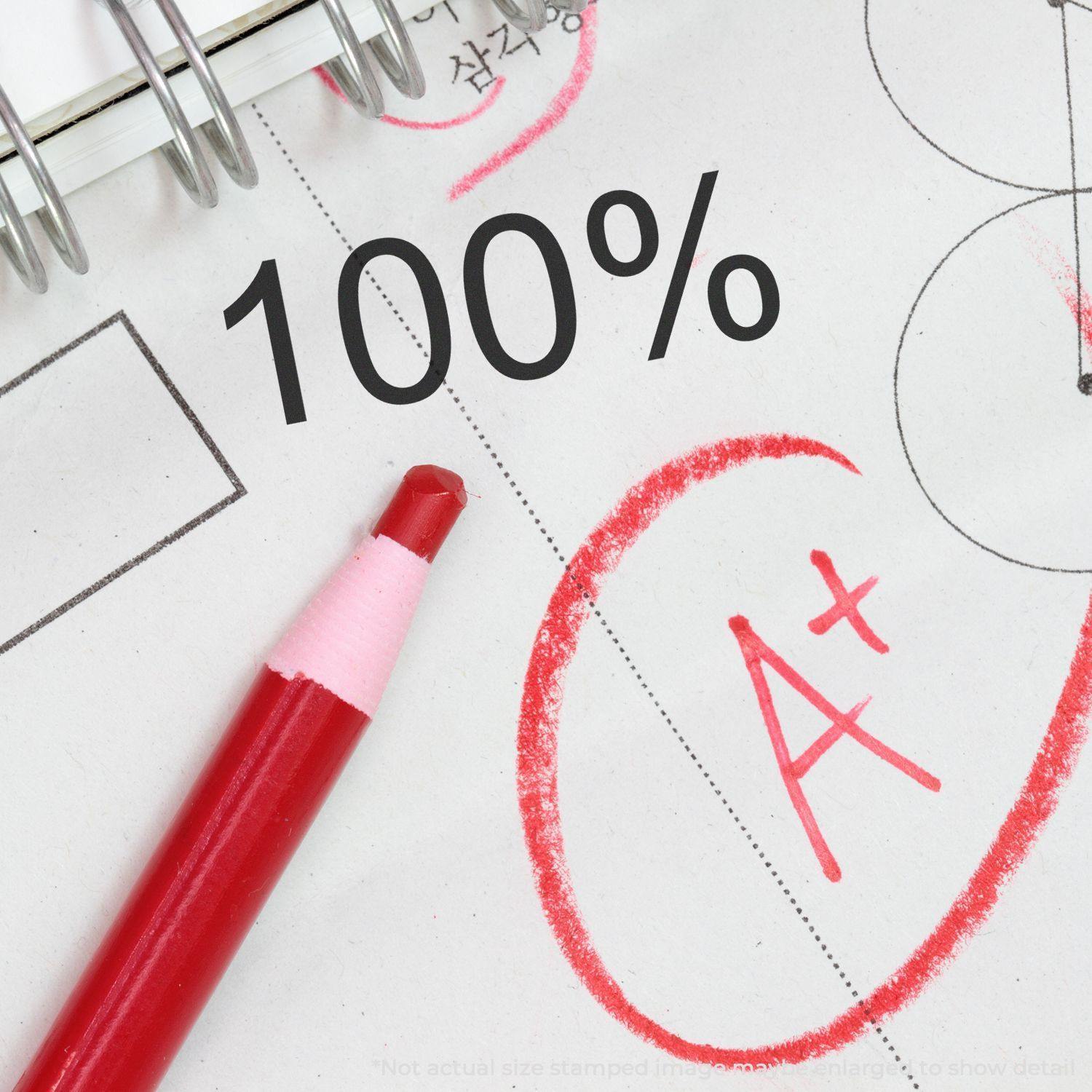 A red pen and a paper with a circled A+ grade and a Large 100 Percent Rubber Stamp mark.