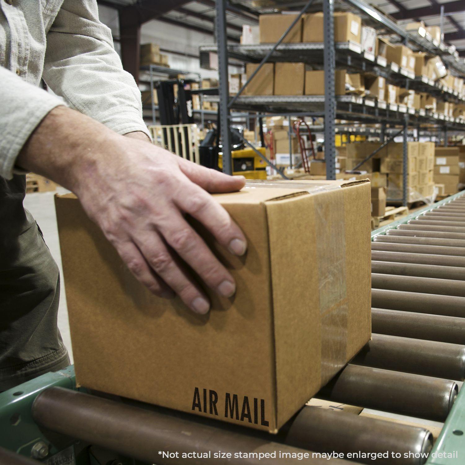 A person places a cardboard box labeled Air Mail on a conveyor belt in a warehouse filled with shelves of boxes.