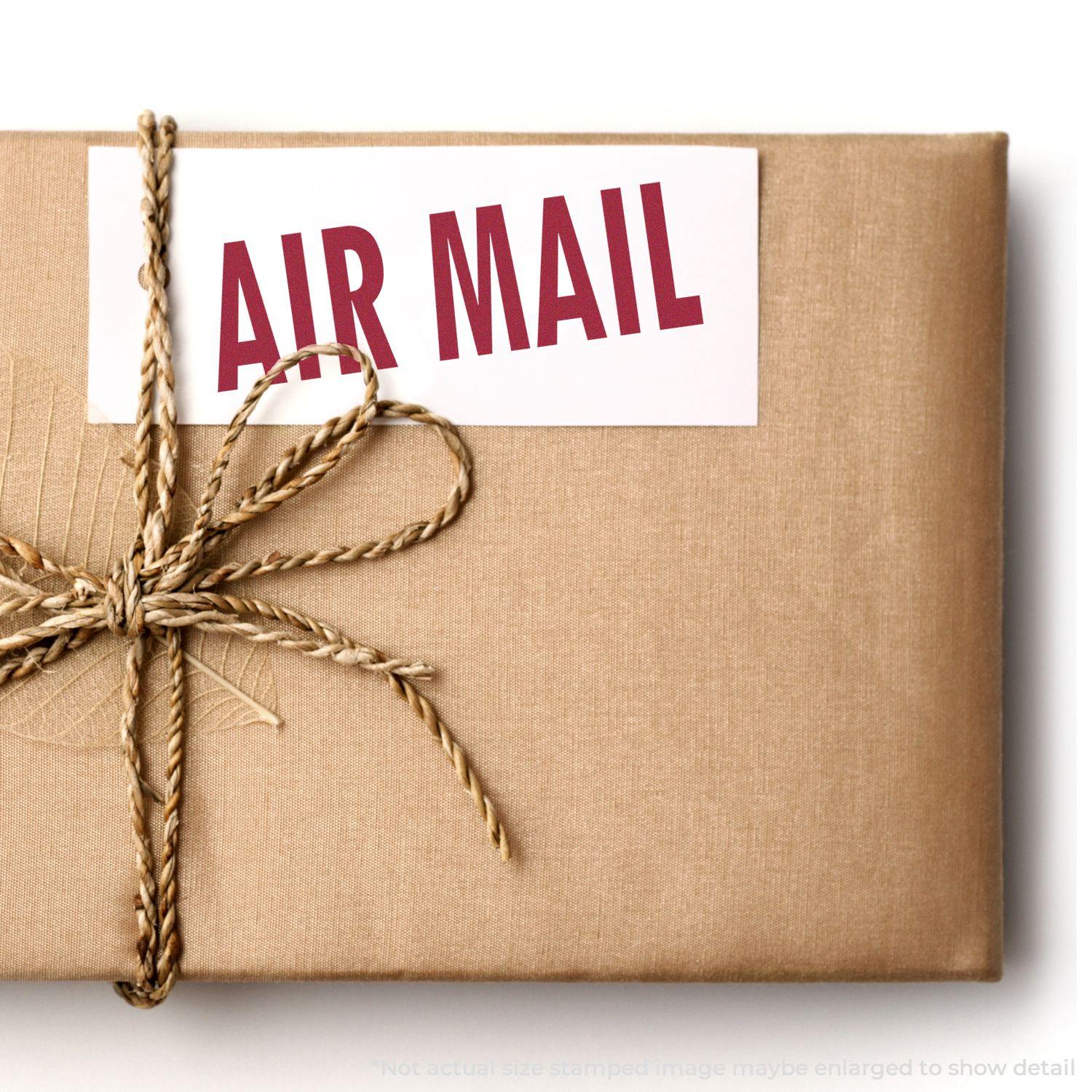 A brown package with a twine bow and a Large Air Mail Rubber Stamp imprint on a white label.