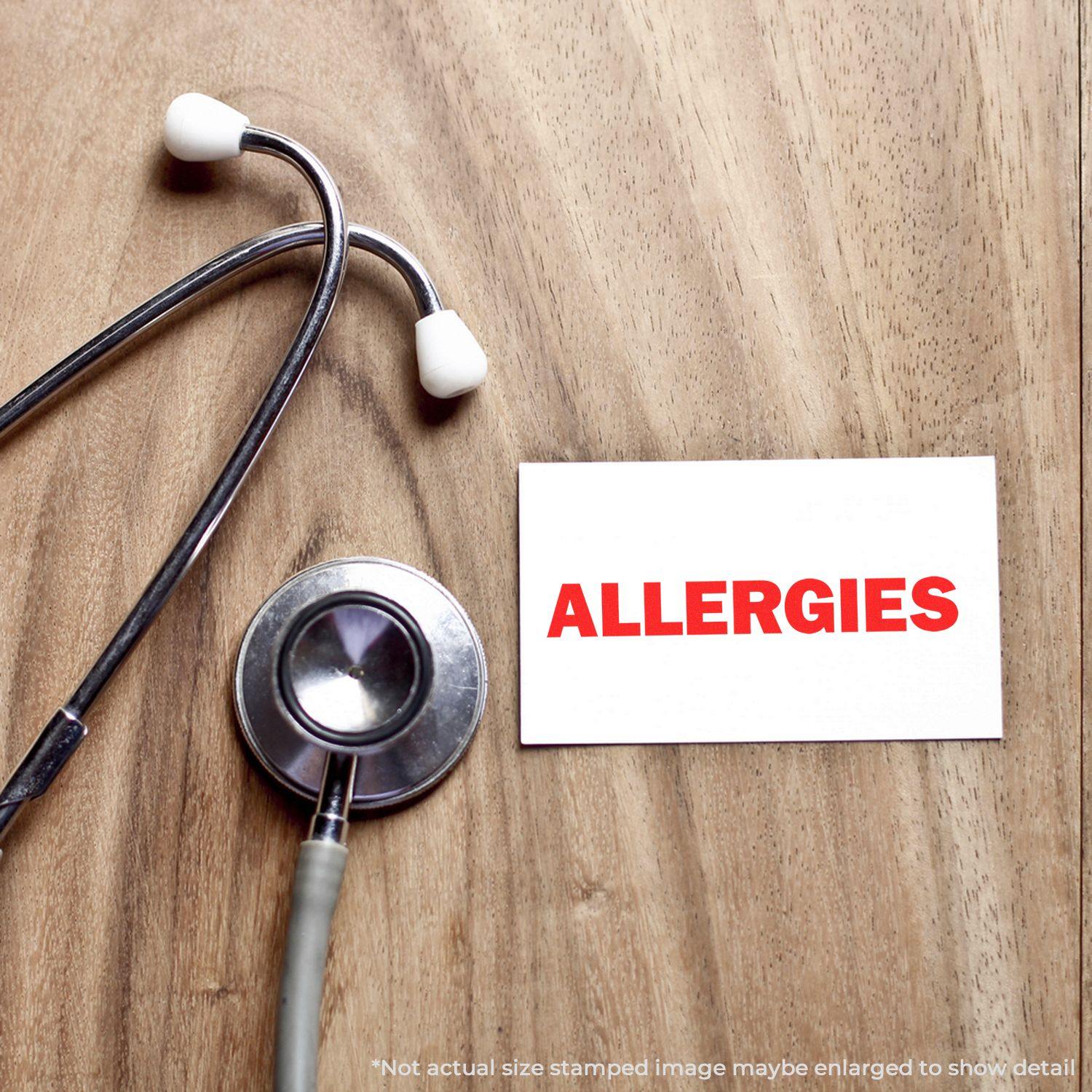 Large Allergies Rubber Stamp in red ink on a white card, placed on a wooden surface next to a stethoscope.