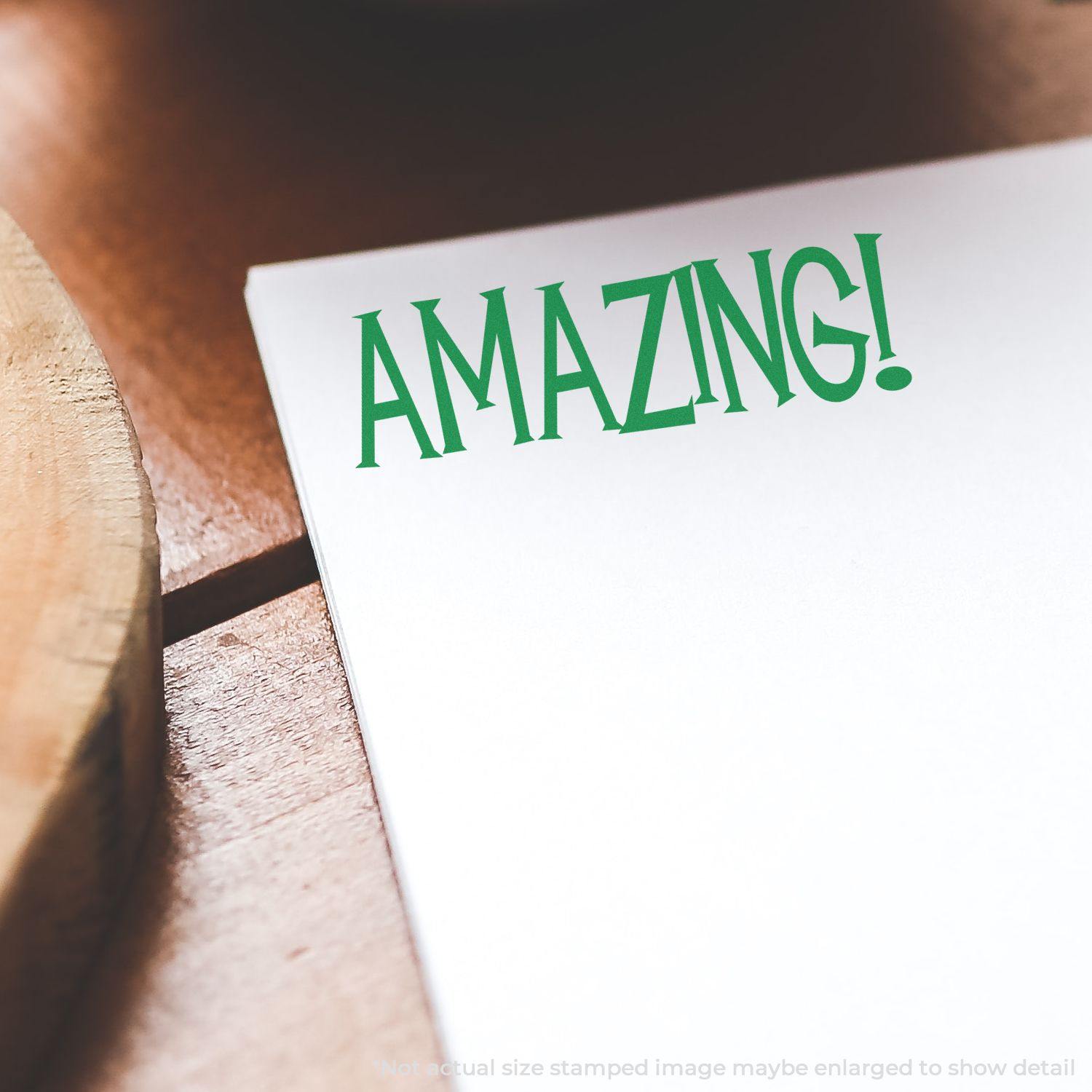 A piece of paper stamped with AMAZING! in green ink using the Large Amazing Rubber Stamp, placed on a wooden surface.