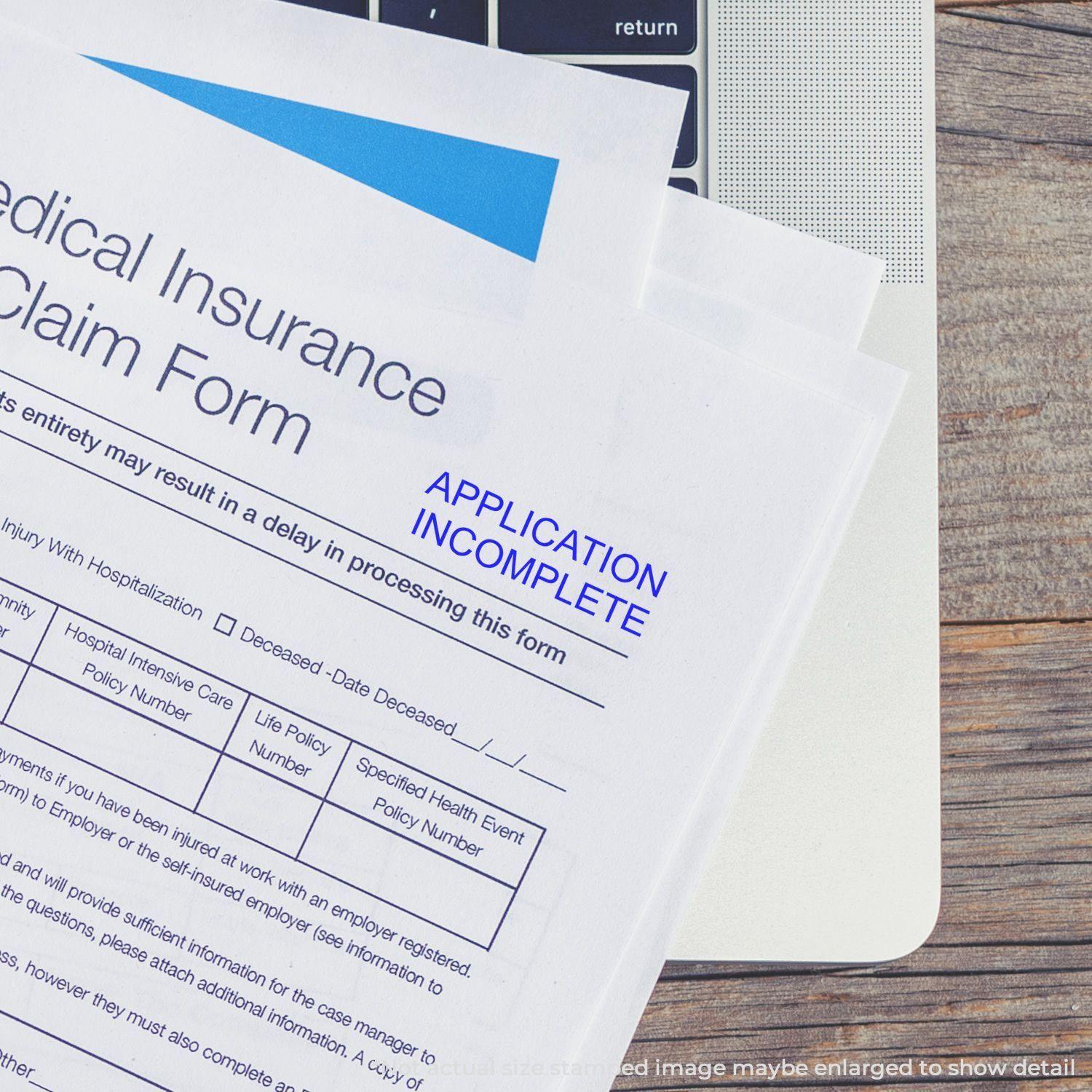 Medical insurance claim form stamped with APPLICATION INCOMPLETE using the Large Application Incomplete Rubber Stamp, placed on a laptop.