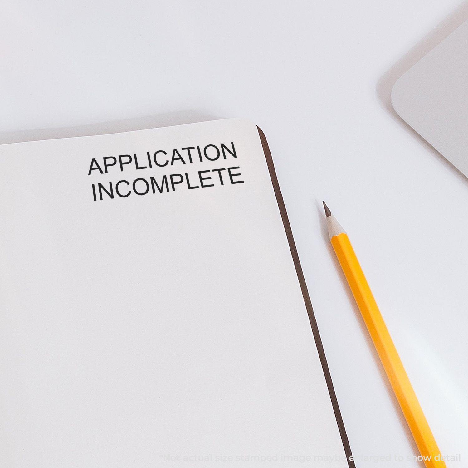 Large Self Inking Application Incomplete Stamp used on a white paper with a pencil beside it on a white desk.