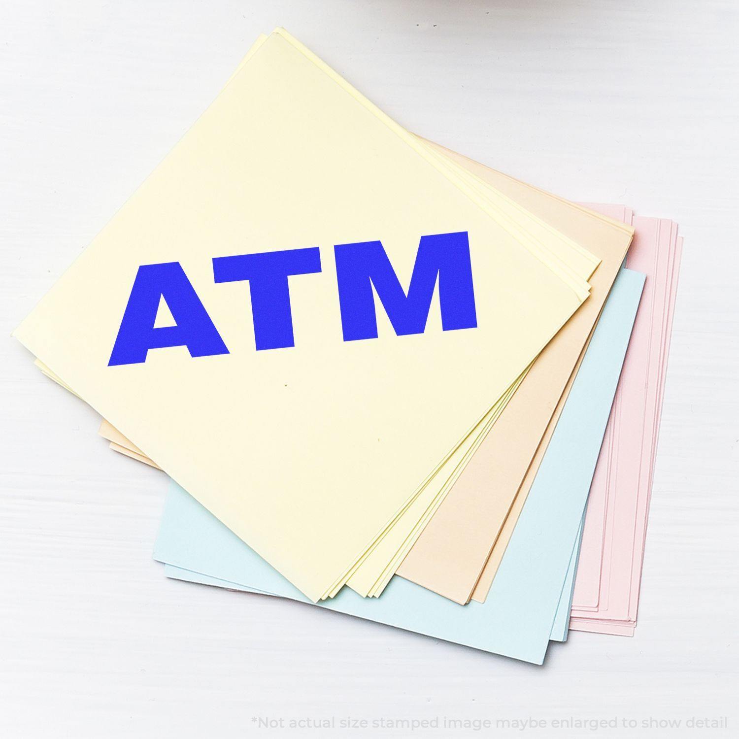 A stack of pastel-colored papers stamped with a blue ATM using a Bank Stamp ATM Rubber Stamp.